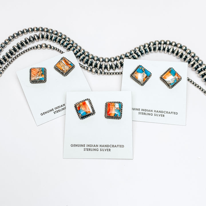 Three turquoise mix studs are in the middle of the picture, on a white background. Navajo pearls are laid above the studs. 