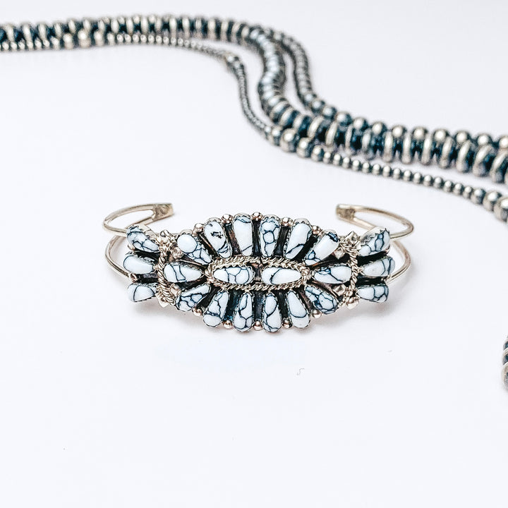 Centered is a cluster white buffalo turquoise stone cuff. Above the cuff is navajo pearls, all on a white background