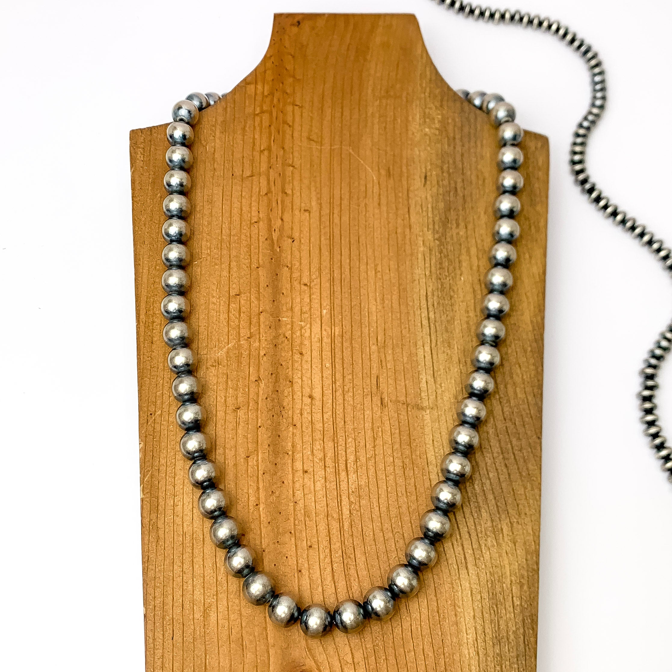 Centered in the picture is a large strand of navajo pearls on a wooden backdrop. 