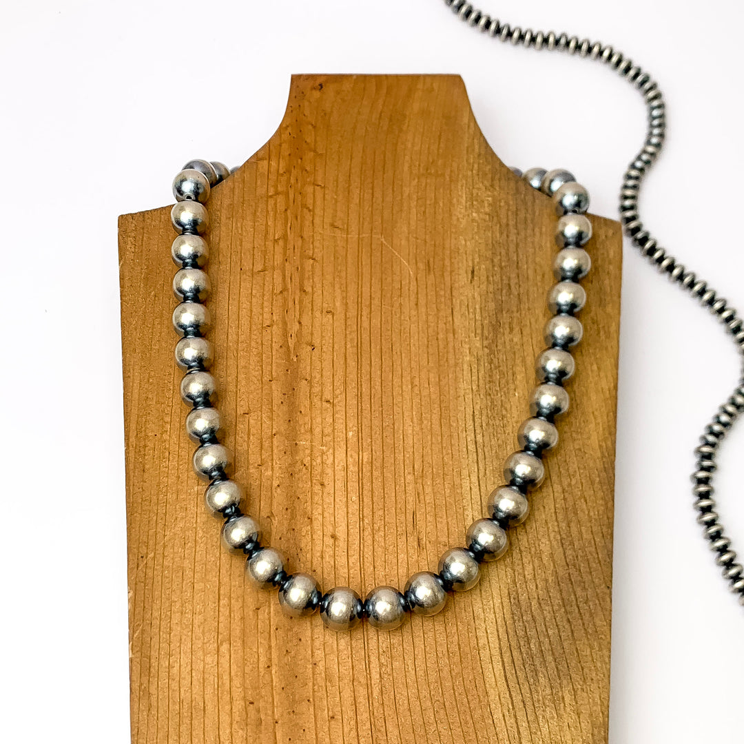 Centered in the picture is a large strand of navajo pearls on a wooden backdrop.