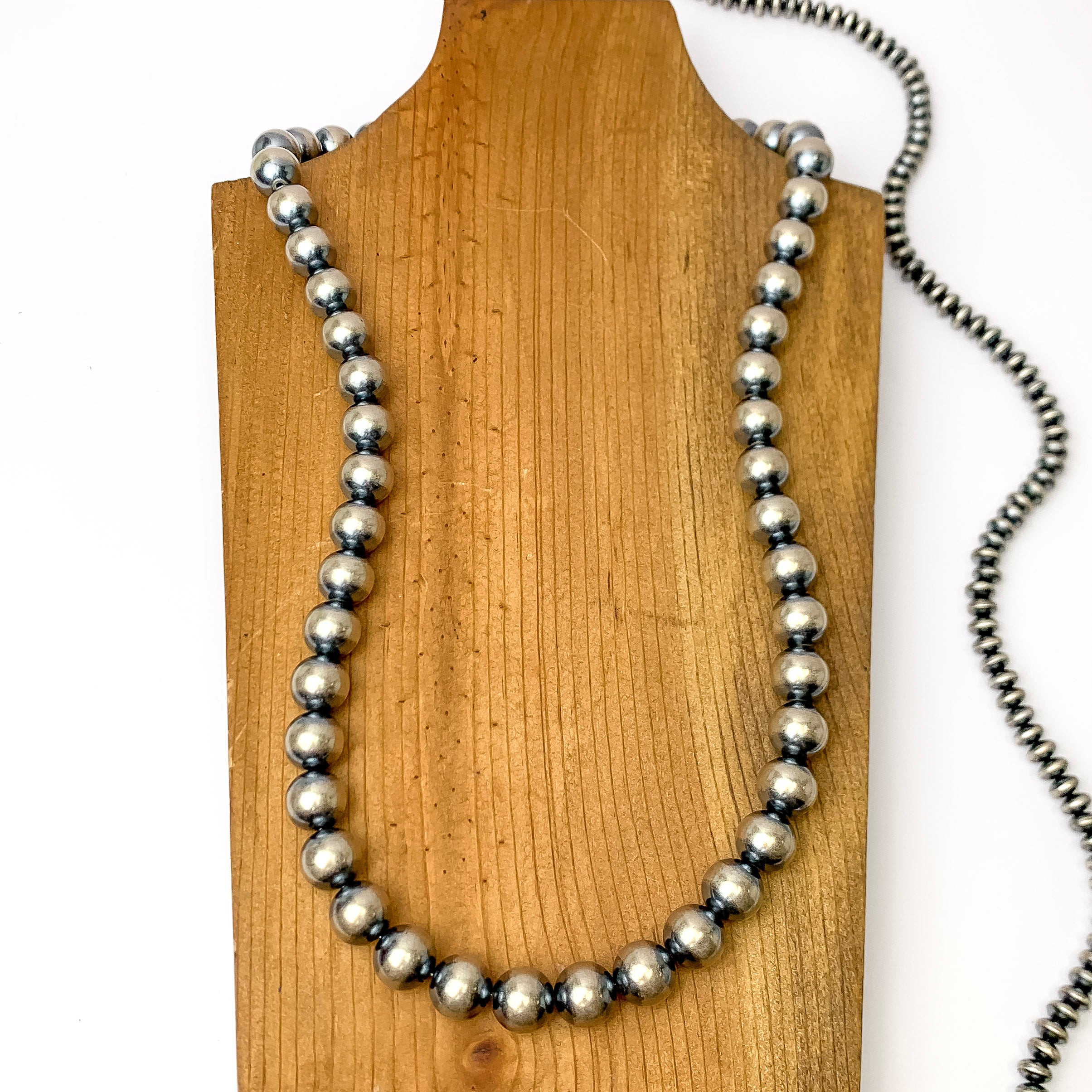 Centered in the picture is a large strand of navajo pearls on a wooden backdrop.