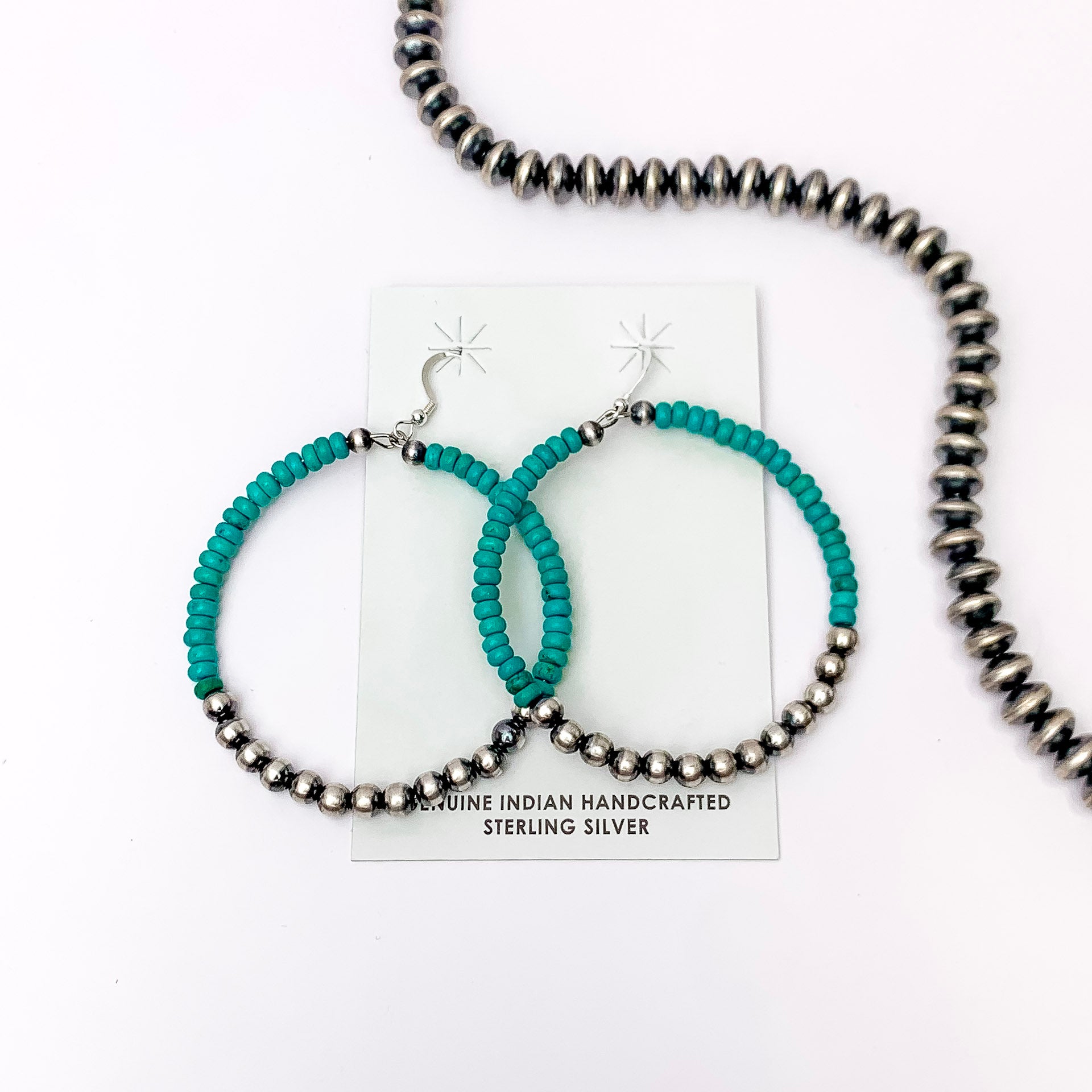 Centered in the picture is a pair of navajo and turquoise hoops on a white background.