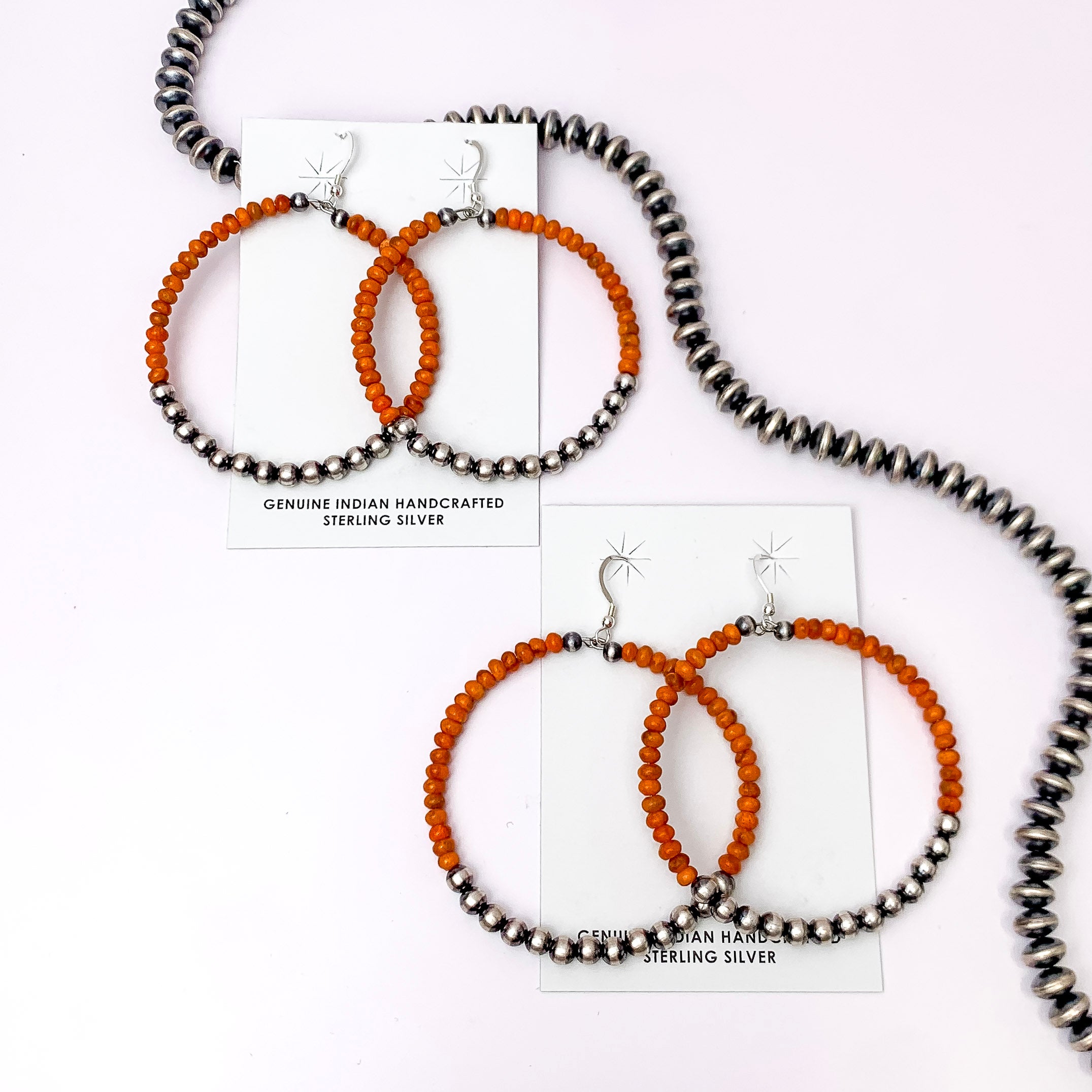 Centered in the picture is orange navajo beaded earrings on a white background. 