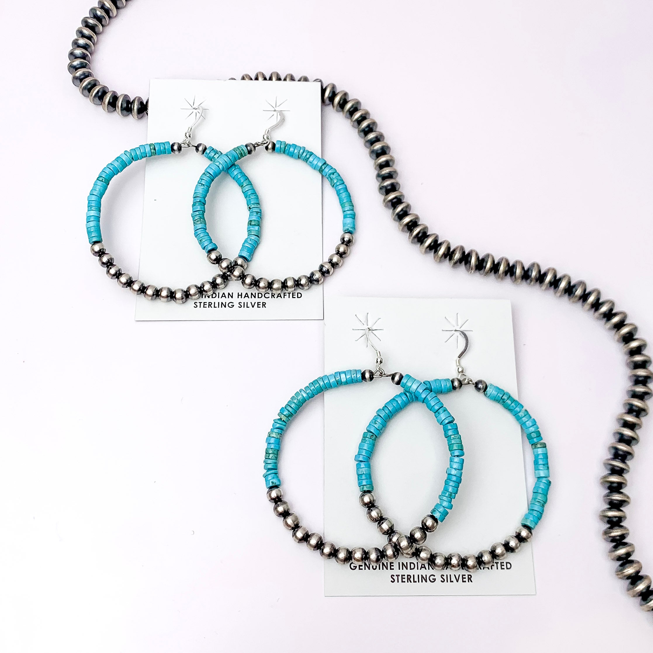 Centered in the picture is 2 pair of navajo and turquoise hoops on a white background. 