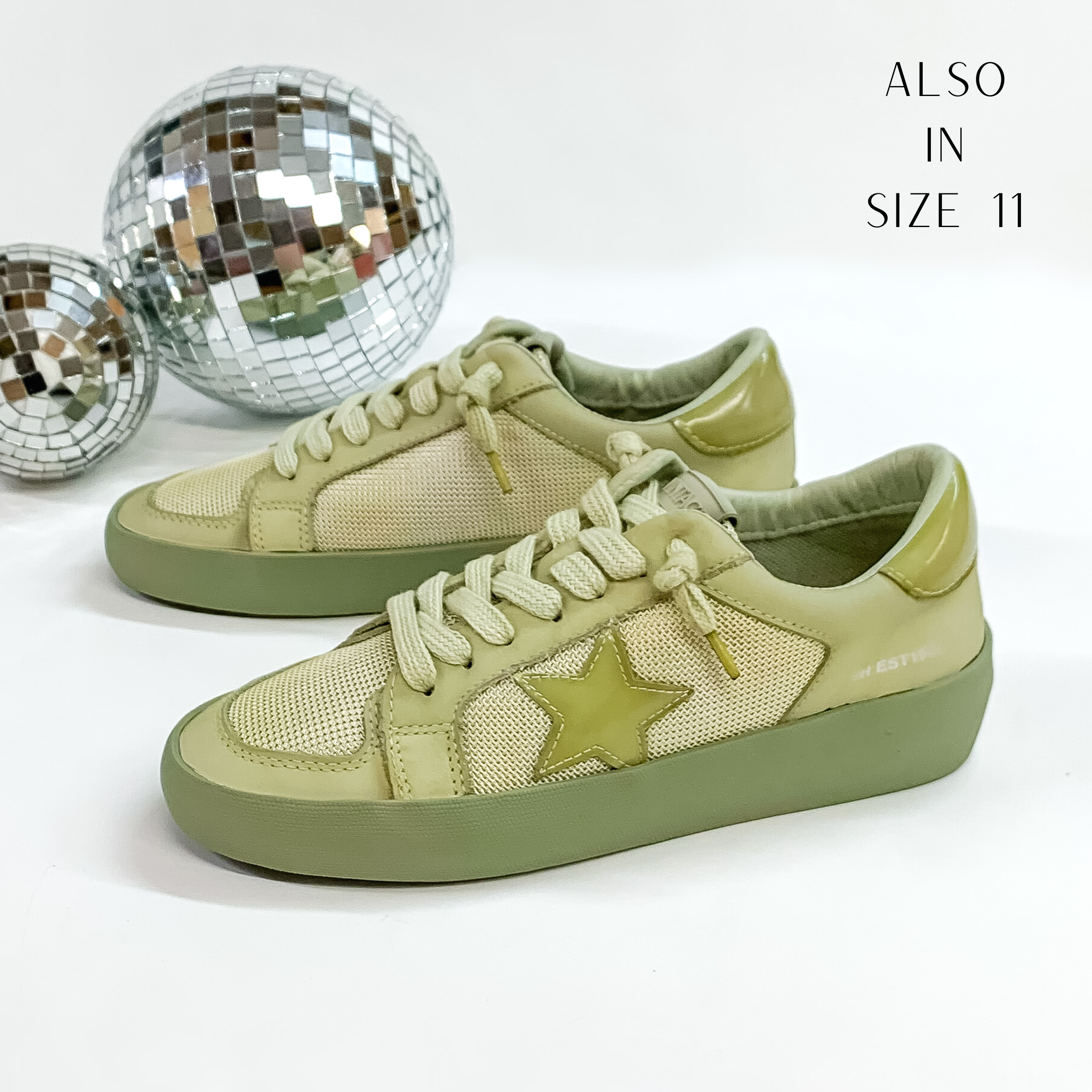 These tennis shoes are an olive green color with green laces and a green star emblem. These tennis shoes are pictured in front of disco balls on a white background.