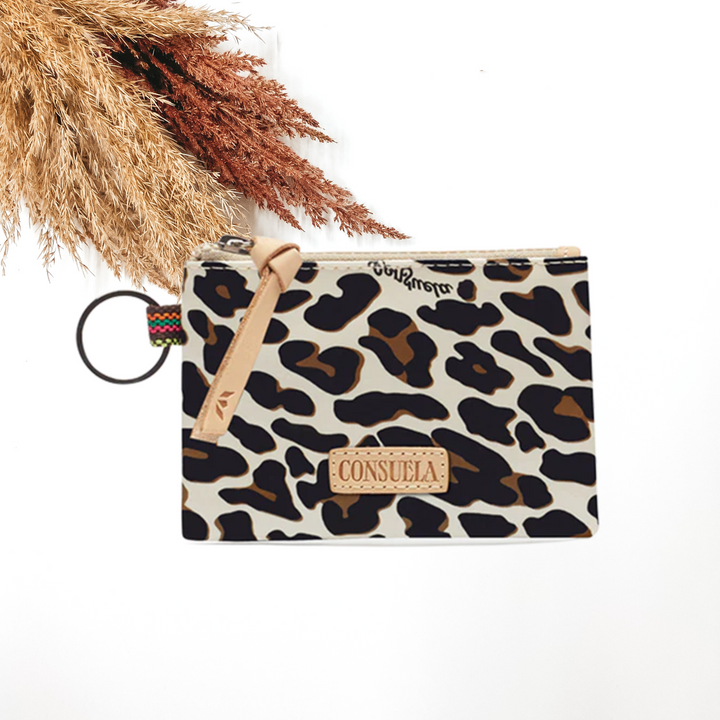 Ivory pouch with a leopard print. This pouch also includes a zipper and a silver key ring. This pouch is pictured on a white background with tan and brown pompous grass in the top left corner. 