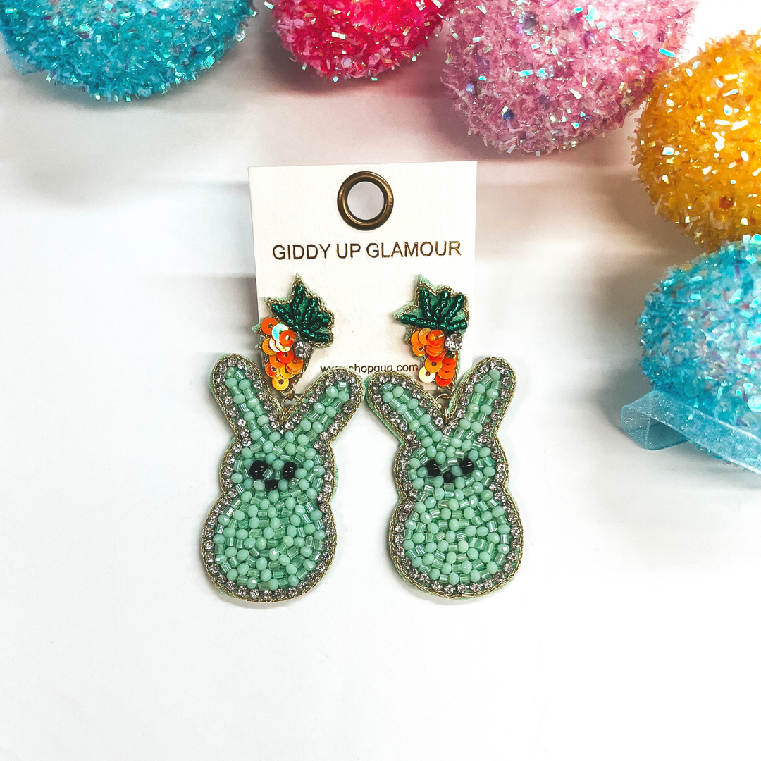 Beaded bunny rabbit earrings on a carrot post. Pictured on white background with colorful Easter eggs.