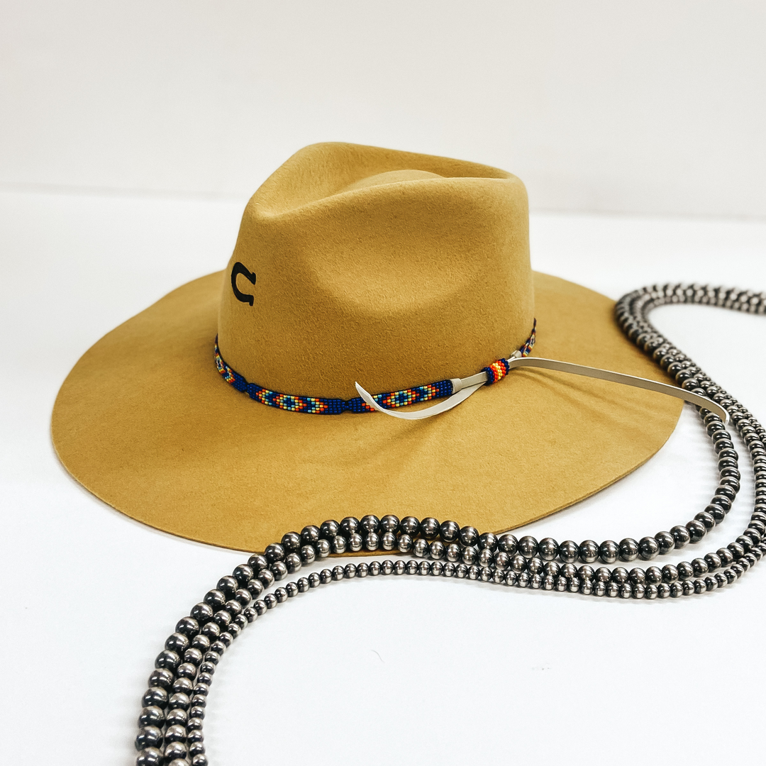 A mustard yellow felt hat with a blue beaded band with tribal patterns. Pictured on white background with Navajo Pearls.