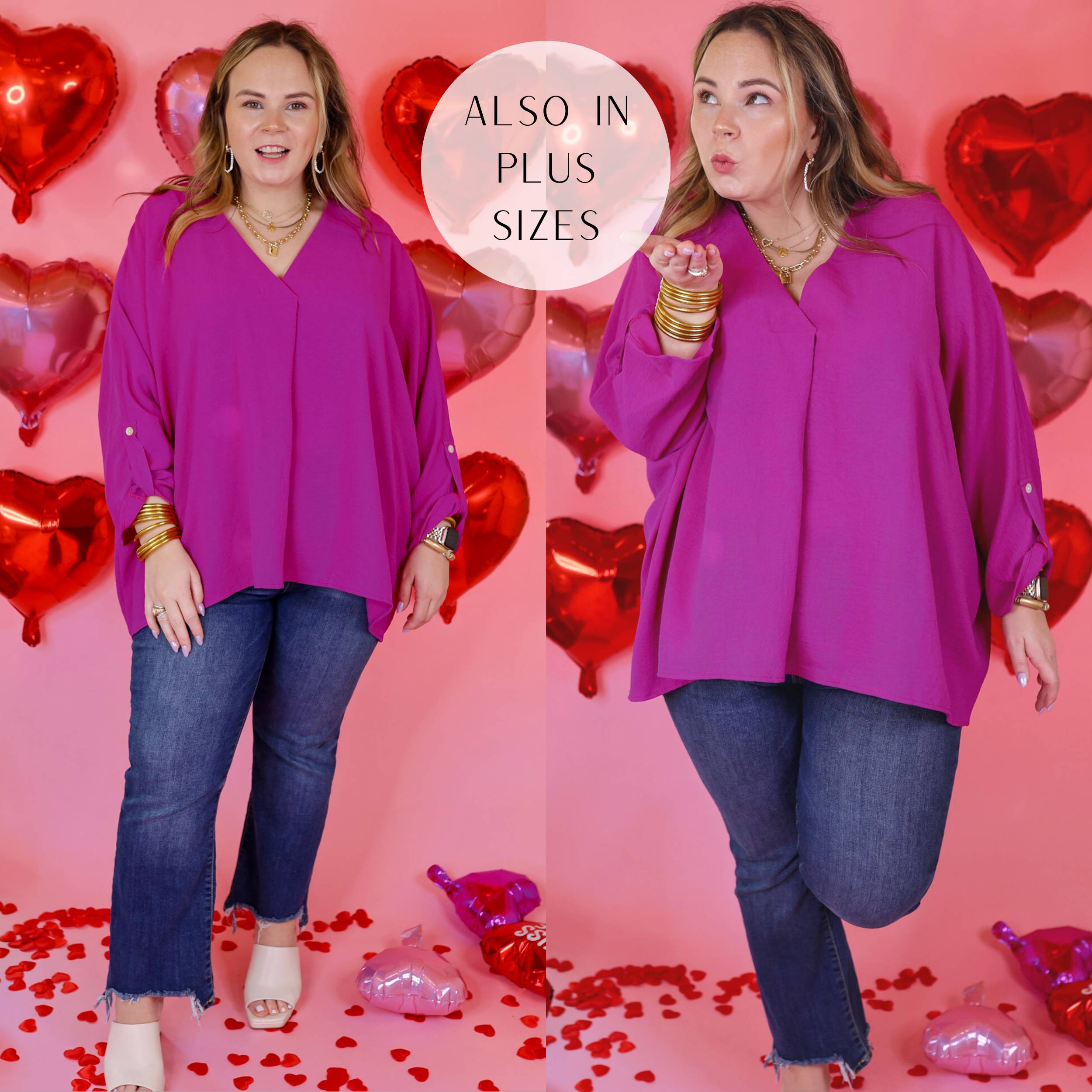 Model is wearing a 3/4 sleeve v neck top in magenta. Model has this top paired with straight leg jeans, white heels, and gold jewelry. Background is light pink with red heart balloons. 