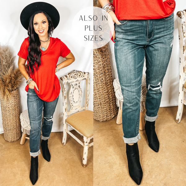 Model is wearing a pair of medium wash boyfriend jeans. The jeans have a whole in the knee that is patched. Model has it paired with a red top, black booties, and a black hat.