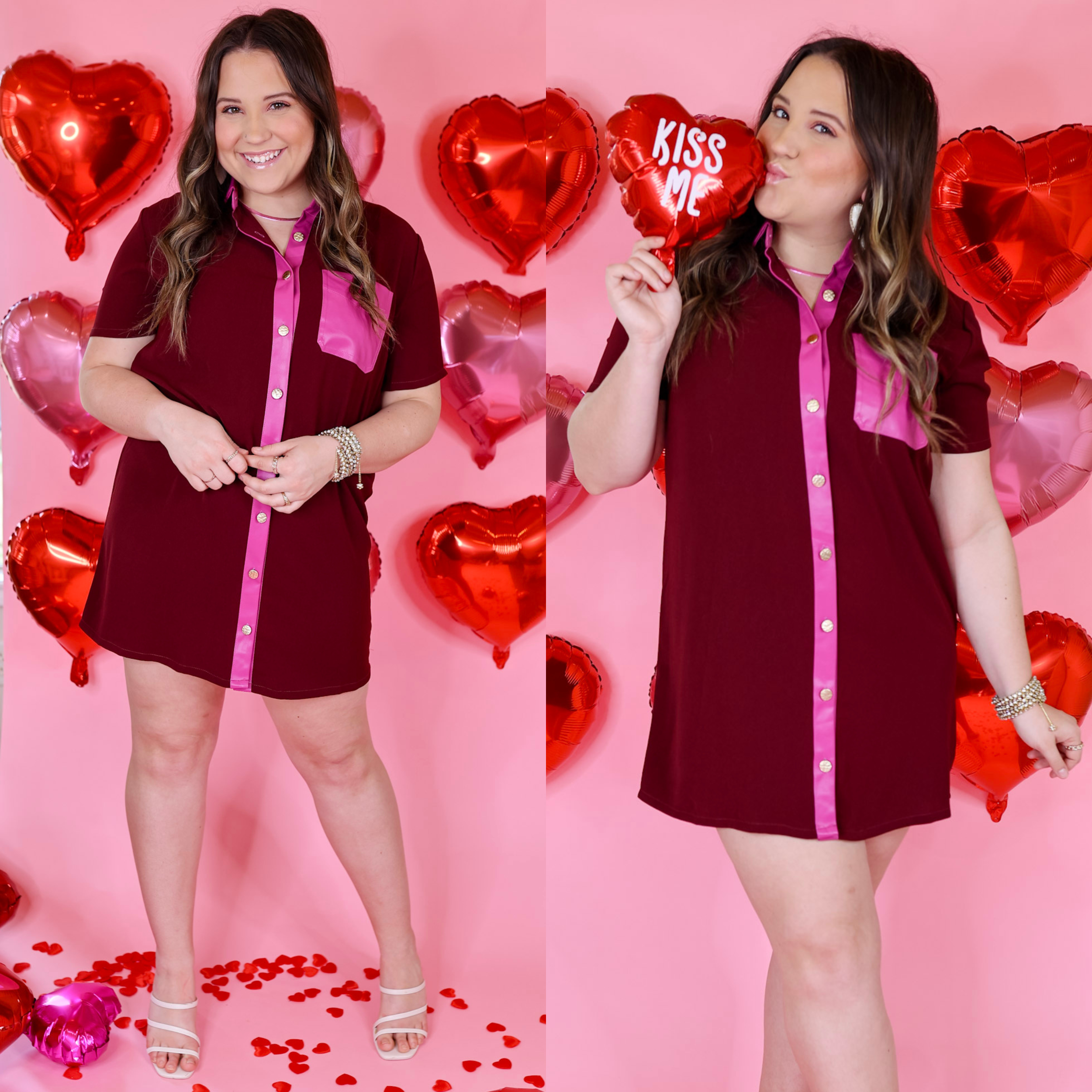Model has a button down, feaux leather trim dress with a front pocket in maroon and a hot pink for the trim and pocket. Model has this dress paired with white heels and silver jewelry. Background is a light pink with red balloon hearts. 