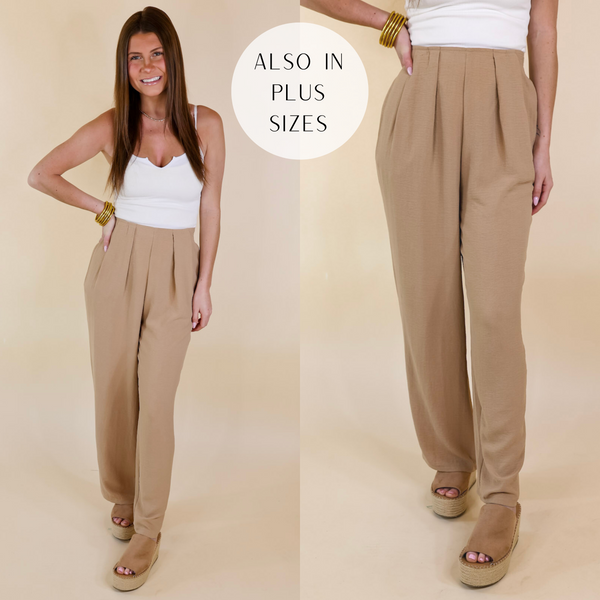 Model is wearing a pair of light tan straight leg pants with pleated detailing on the front waistline. Model has these pants paired with tan wedges, a white tank top, and gold jewelry.