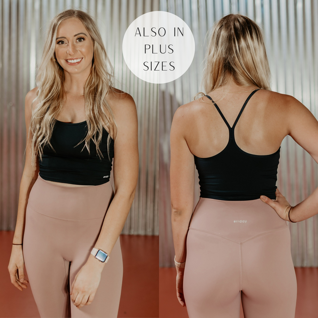 Model is wearing a black spaghetti strap sports bra. Model has it paired with dusty pink leggings, gold jewelry, and a smart watch.