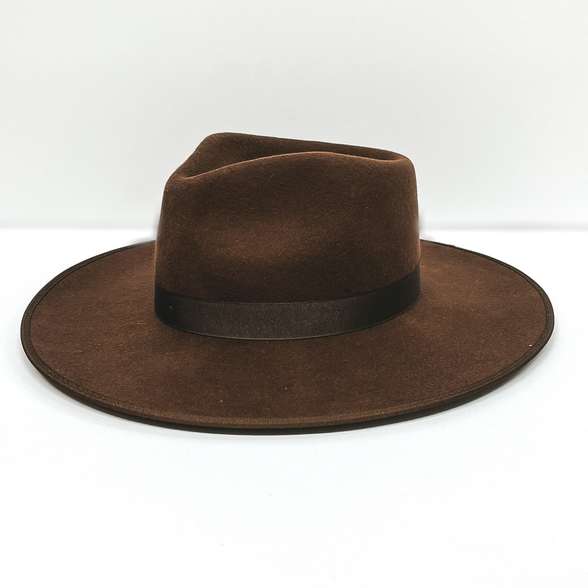 A dark brown felt hat with a ribbon band pictured on a white background.