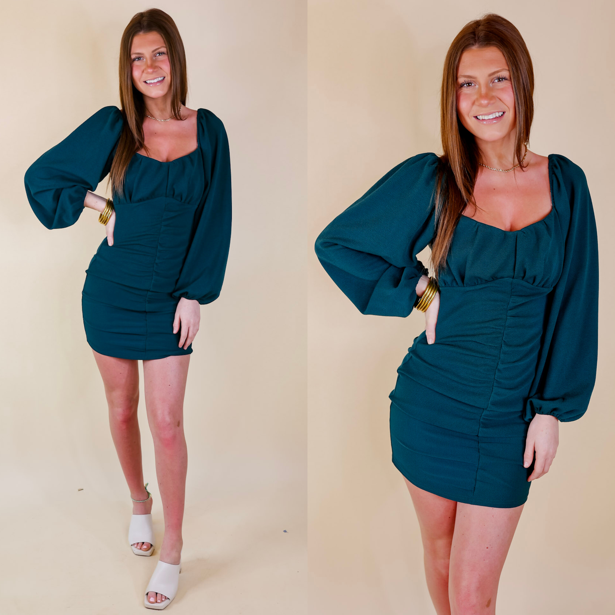 Model is wearing a teal short dress with ruching up the front and long balloon sleeves. Model has this dress paired with gold jewelry and white heels.