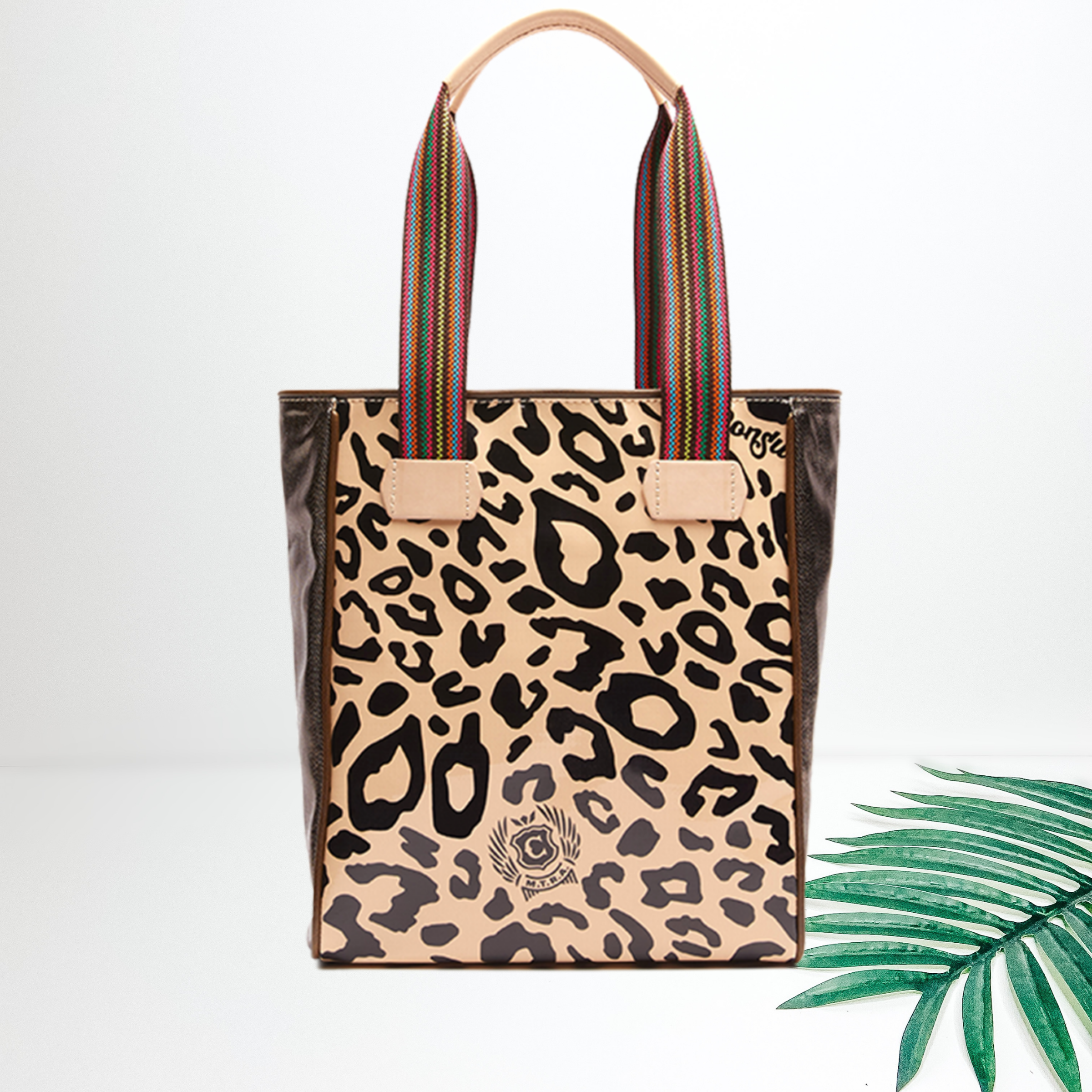 Centered in the picture is a tote bag in tan cheetah. To the right of the tote is a palm left, all on a white background.