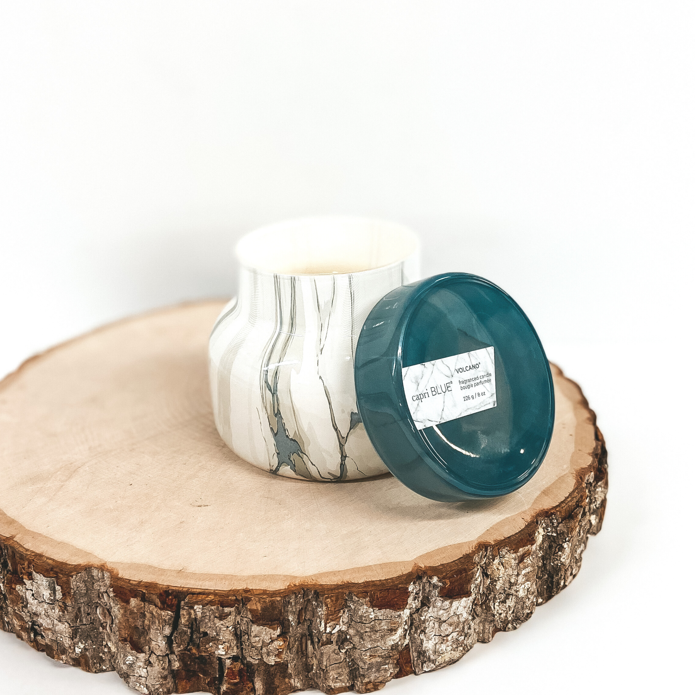 An ivory and blue marble candle with a blue lid pictured on wooden display.
