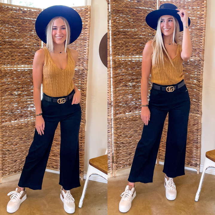 Model is wearing a pair of black cropped pants. Model has it paired with a black belt, white sneakers, and a mustard yellow tank top.