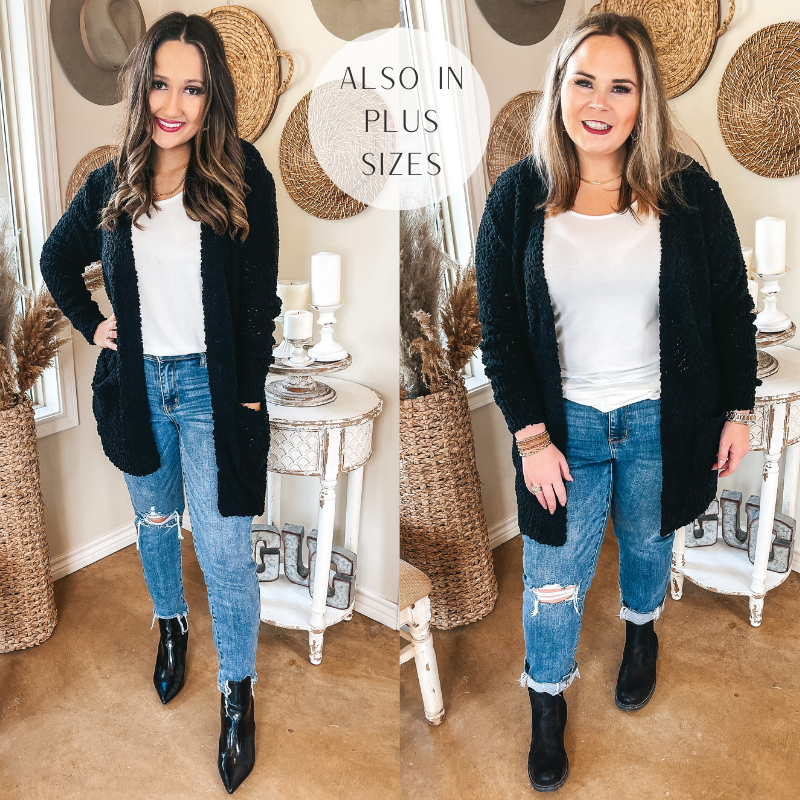 Models are wearing a black popcorn knit cardigan. Both models have it on over an ivory tank top, distressed skinny jeans, black booties, and gold jewelry.