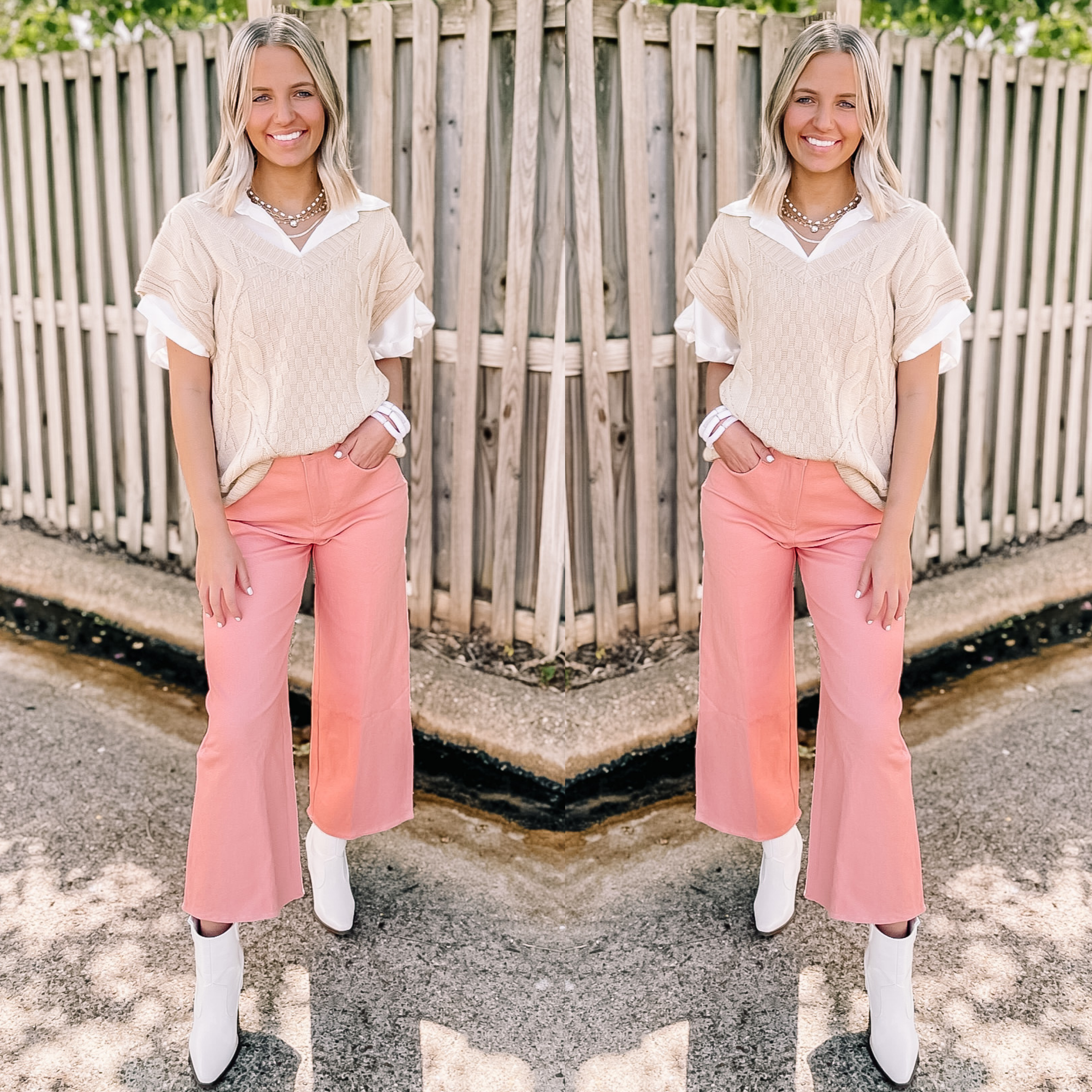 Model is wearing wide leg cropped denim jeans in pink. Model has it paired with white booties and a cream sweater top on top of a white blouse. 