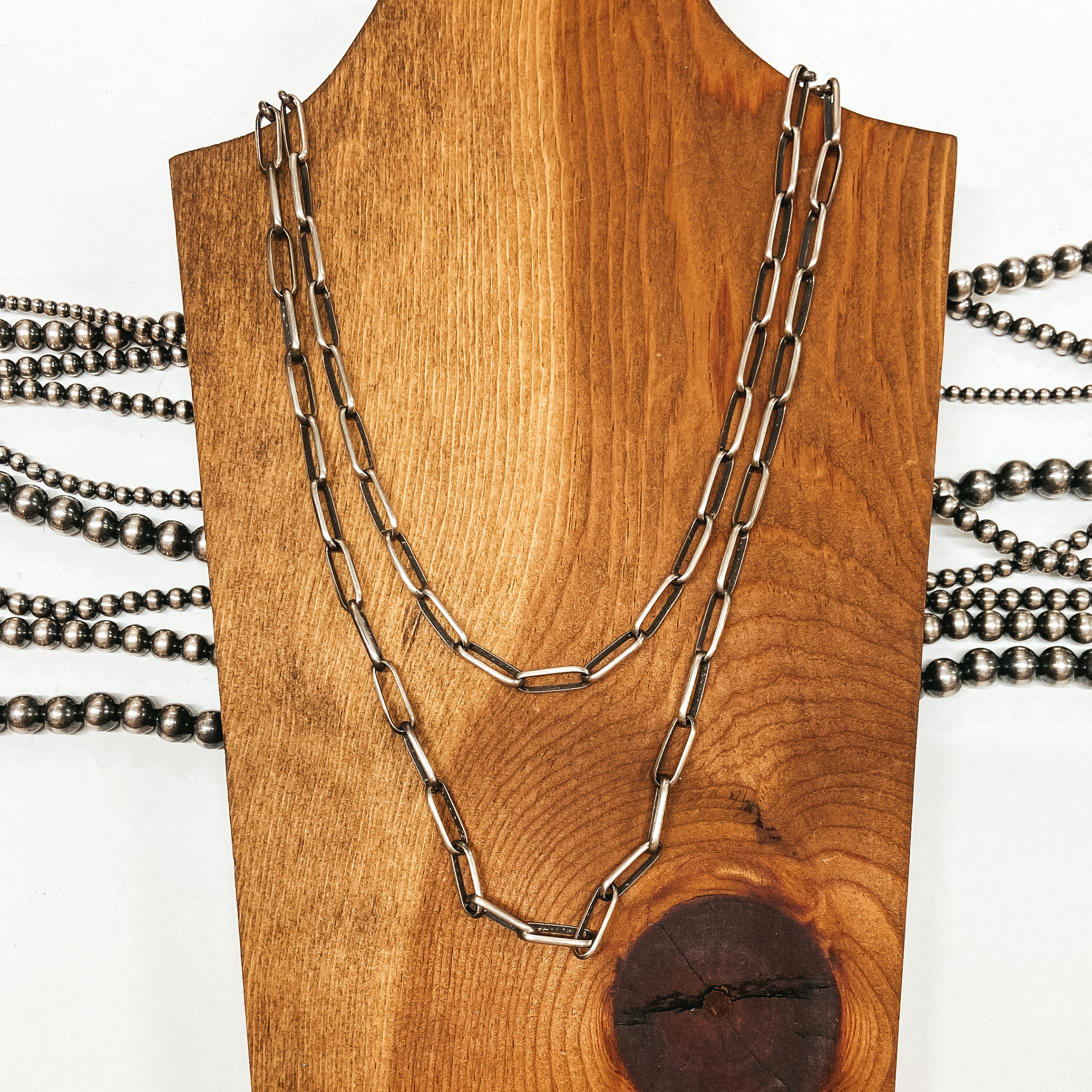 Sterling silver chain link necklace two strands placed on wooden slat. Pictured on white background with Navajo pearls.