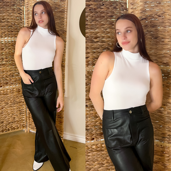 Model is wearing a high neck, ribbed tank top in white. She is also wearing black leather pants with white booties , gold rings and earrings.