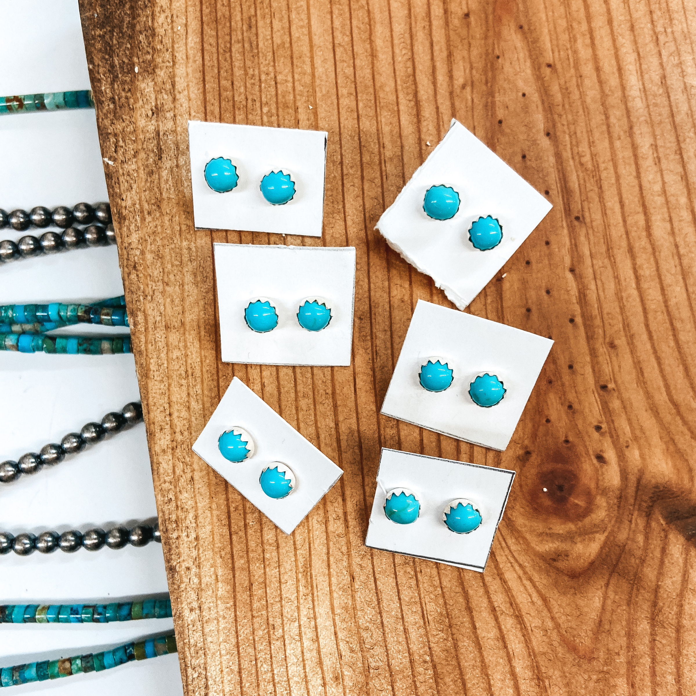 Sterling silver and genuine turquoise stud earrings placed on wooden slat.
