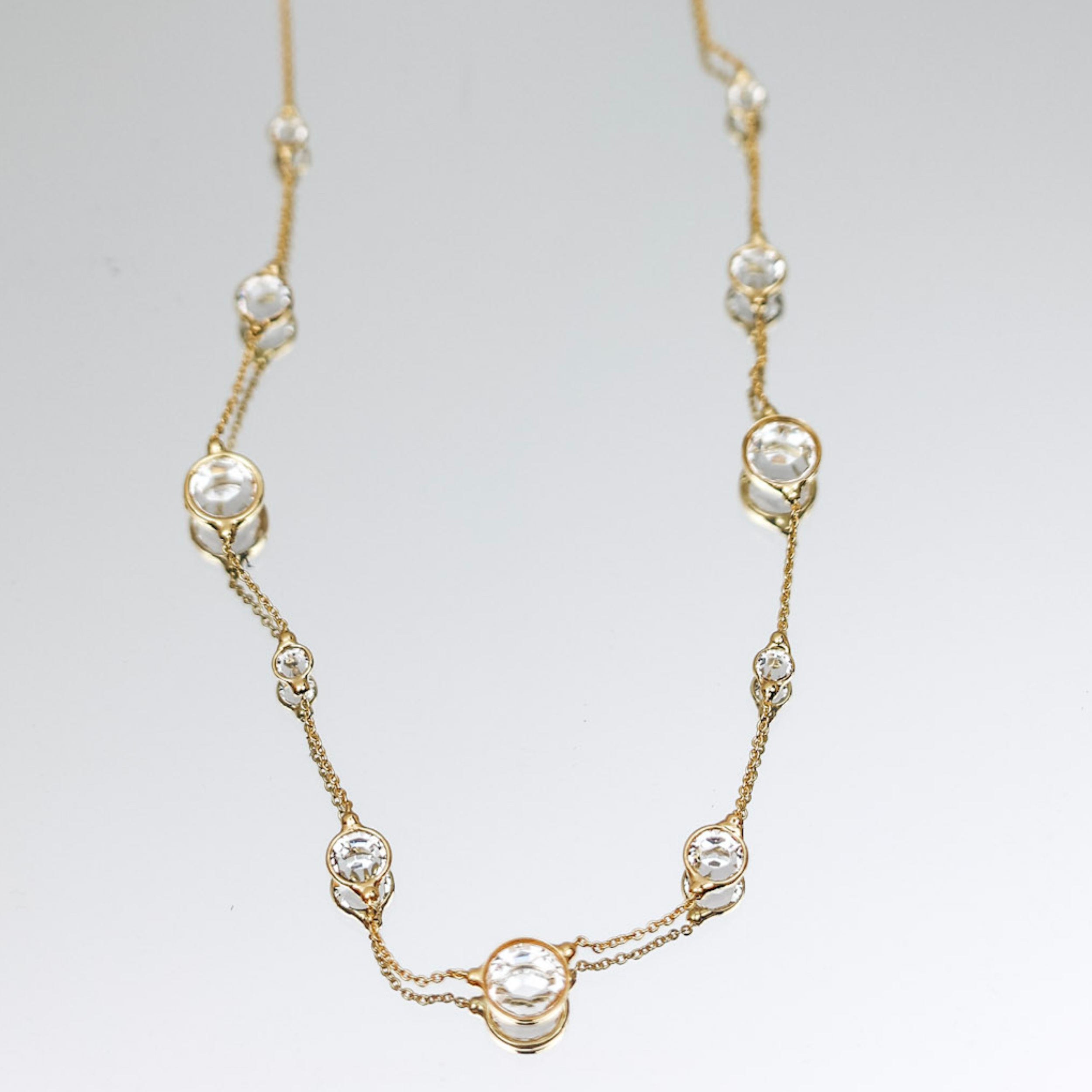 A gold tone necklace with clear circle crystals going around the gold chain.