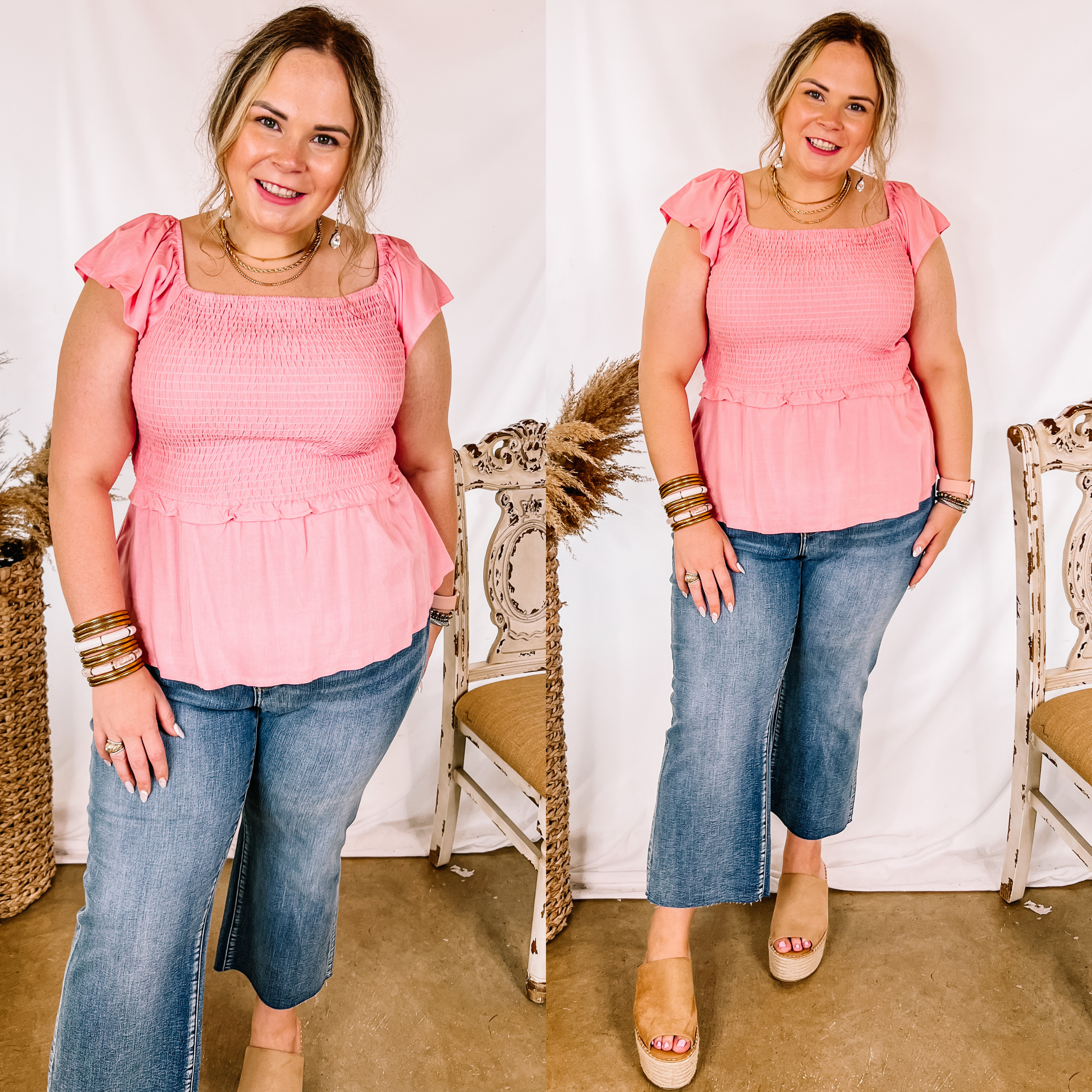 Model is wearing a coral pink top with a smocked bodice and a peplum hem. Model has it paired with tan wedges, cropped jeans, and gold jewelry.