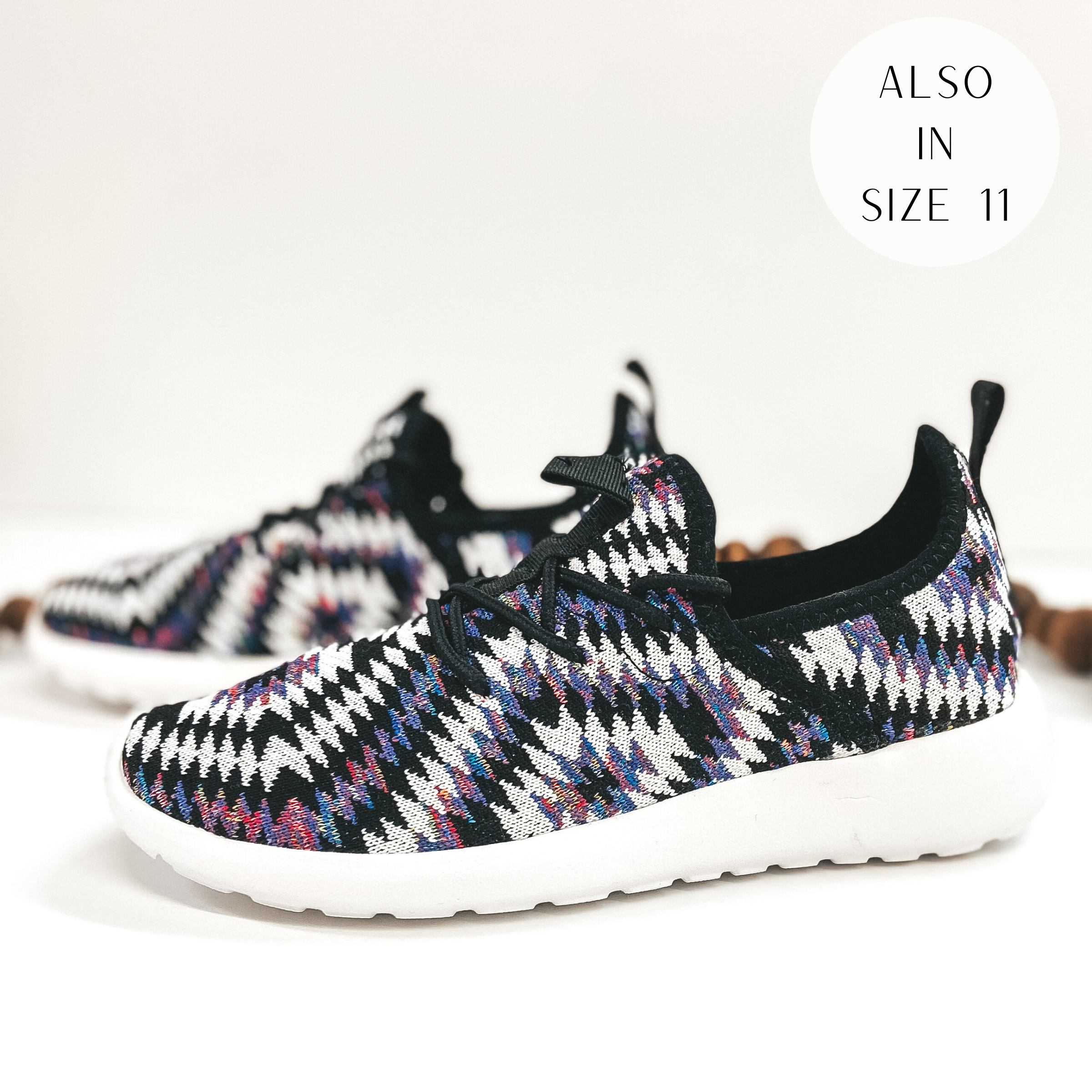 A pair of purple and black aztec print sneakers. Pictured on white background with brown beads.