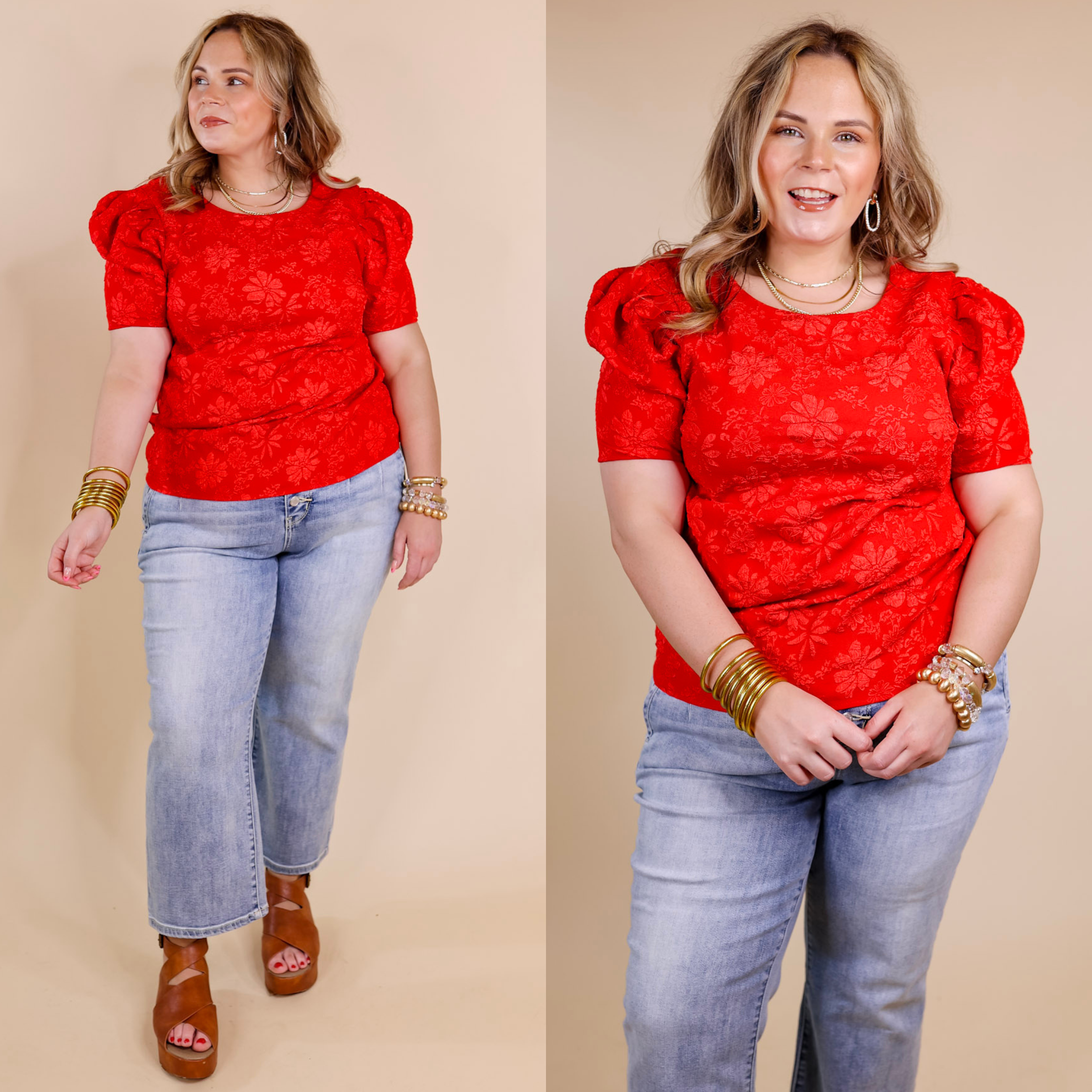 Model is wearing a floral embossed top with short puff sleeves in a bright red color. Model has it paired with light wash jeans, tan sandals, and gold jewelry.