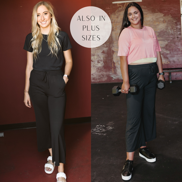 Models are wearing a pair of black sweatpants. SIze small model has it paired with a black top and white sandals. Plus size model has it paired with a pink top and black sneakers.