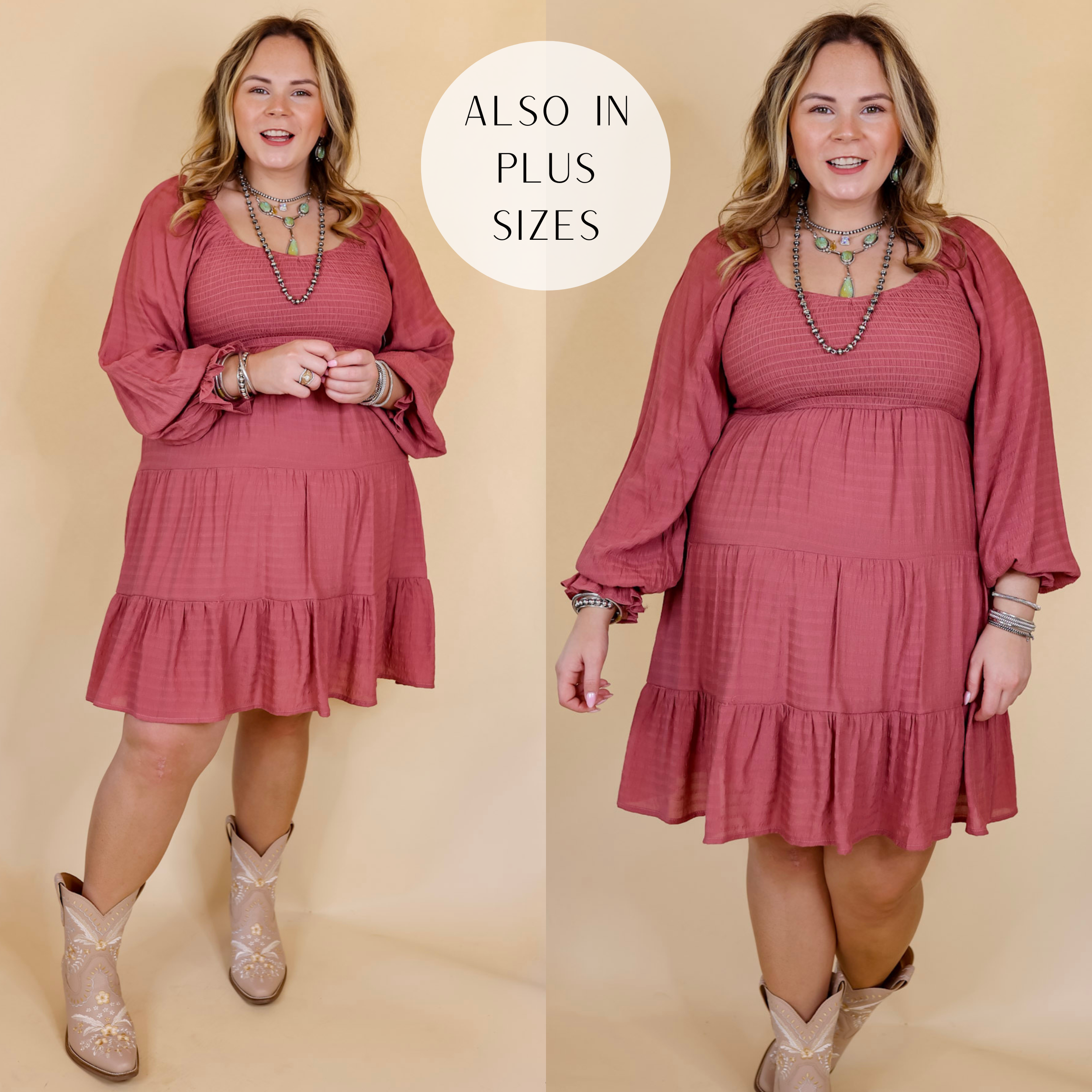 Model is wearing a long sleeve floral dress with a smocked bodice in mauve. Model has this dress paired with tall, white boots and Navajo jewelry. Background is solid tan.
