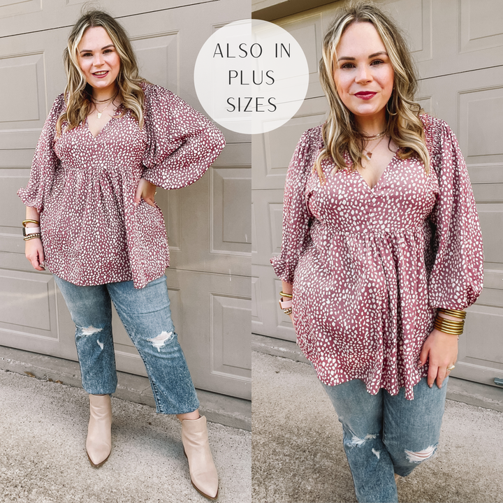 Model is wearing a dotted v neck babydoll top that is mauve pink. Model has it paired with distressed boyfriend jeans, taupe booties, and gold jewelry.