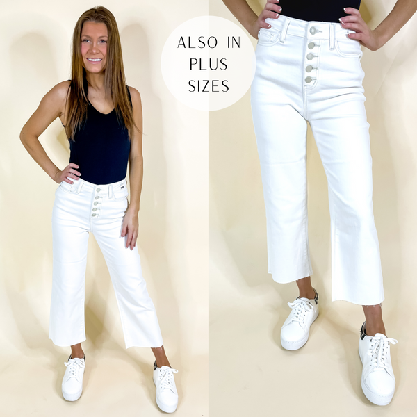 Model is wearing a pair of white jeans that have a button fly and a cropped wide hemline. Model has these jeans paired with a black tank top and white sneakers.