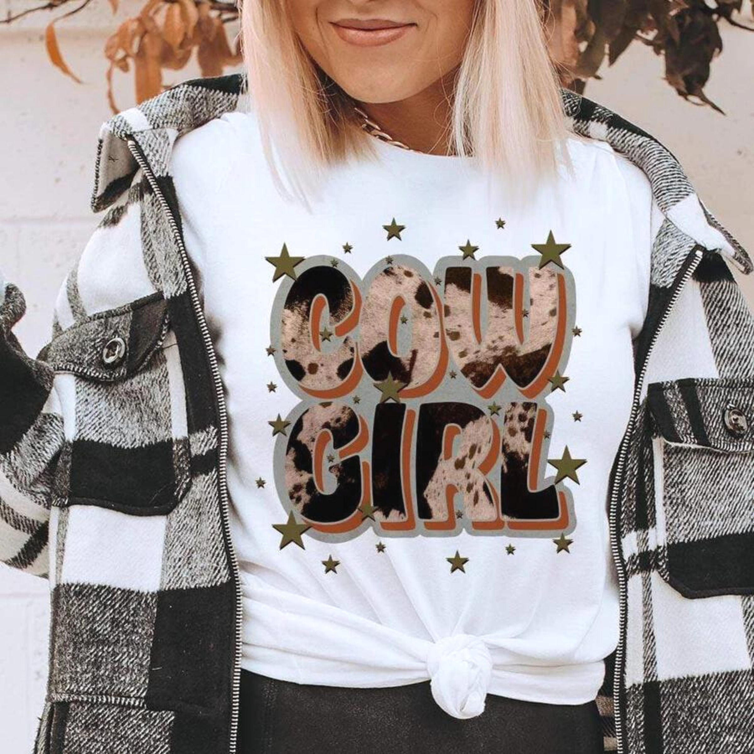 Model is wearing a white tee shirt that says "Cowgirl" in a cowhide print with stars.