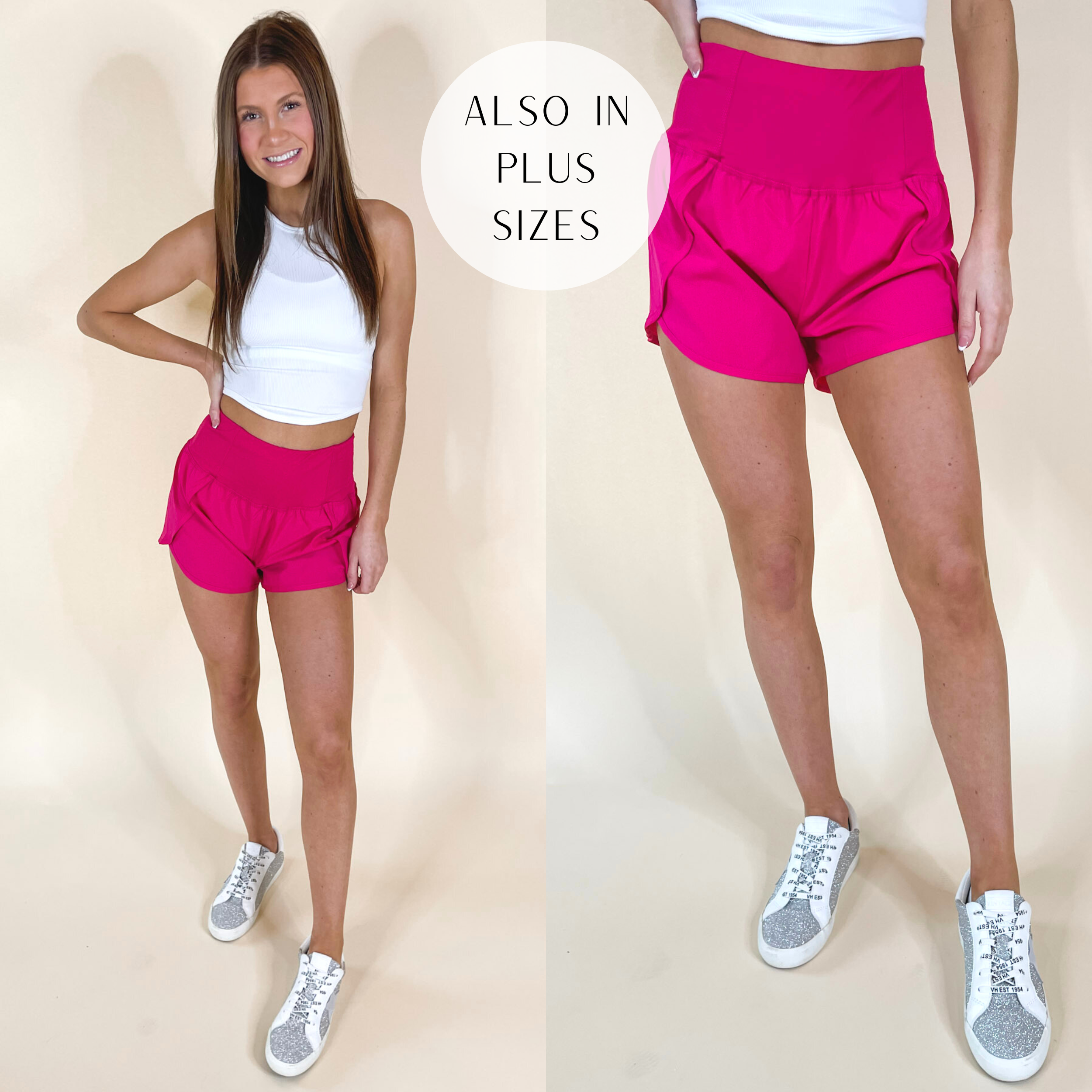 Model is wearing a pair of hot pink wind shorts with a high waist band. Model has these shorts paired with white sneakers and a white tank top.