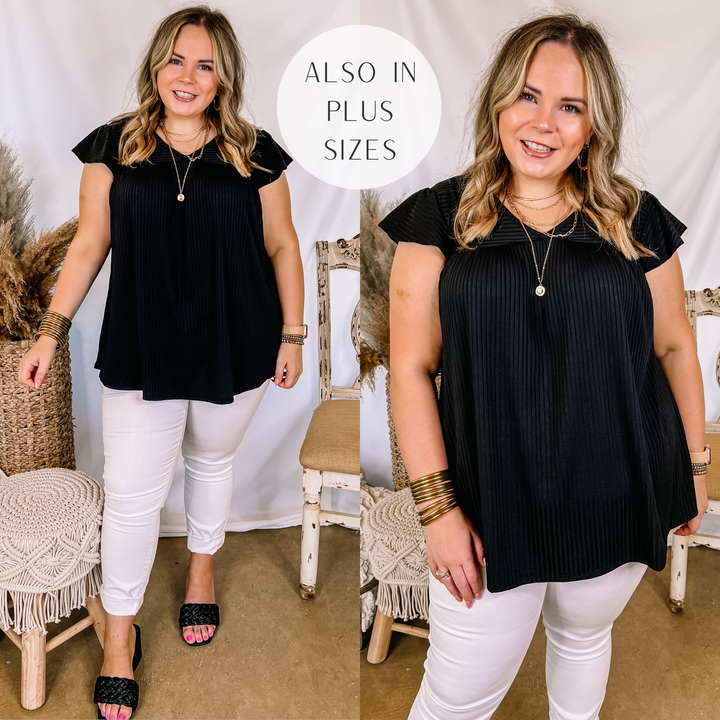 Model is wearing a black ribbed top that has ruffle cap sleeves and a babydoll fit. Model has it paired with white skinny jeans, black heels, and gold jewelry.