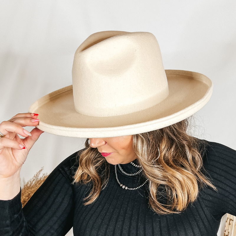 Model is wearing an ivory rancher hat with a flat brim with rolled edges. 