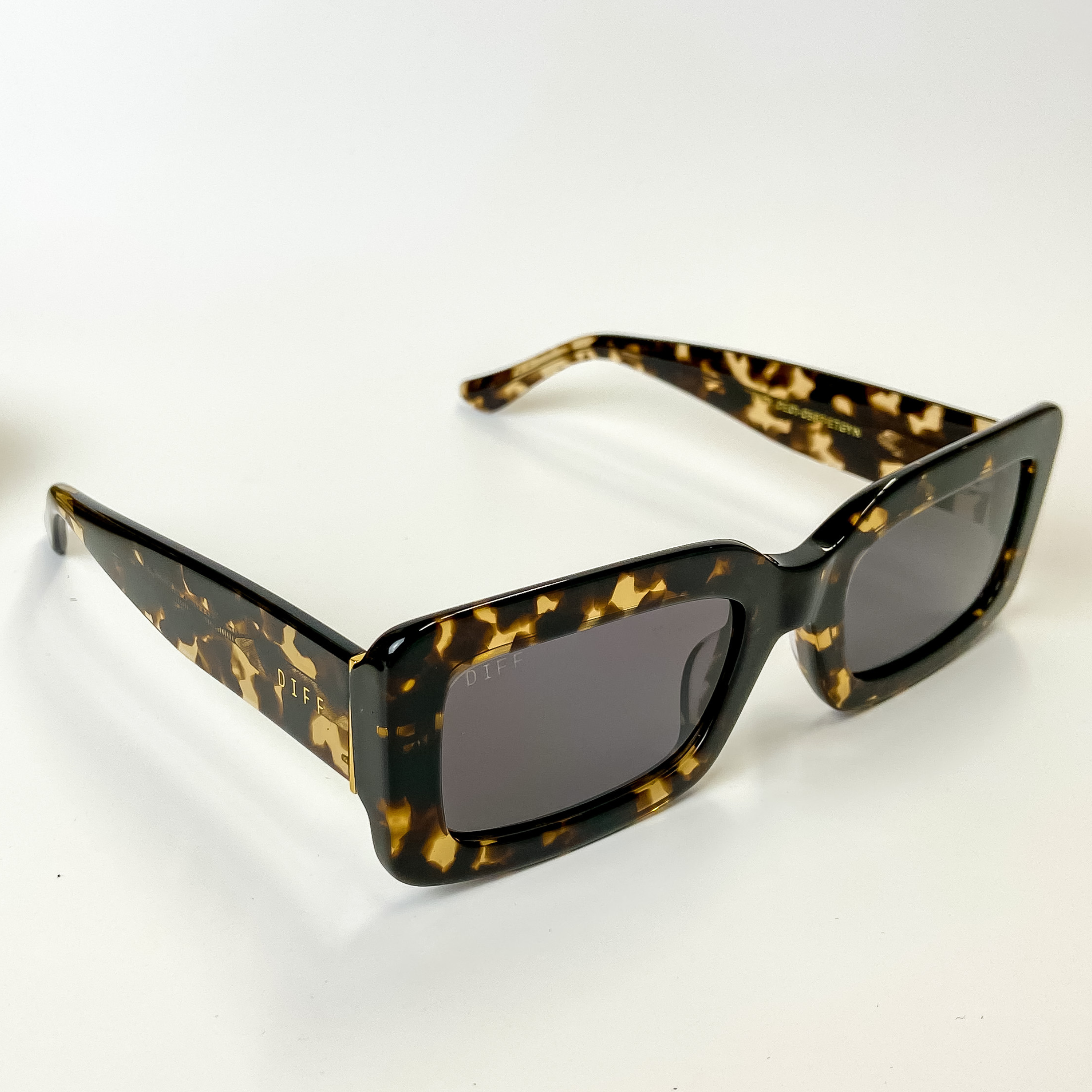 A pair of brown tortoise print frame sunglasses with grey lenses. These sunglasses are pictured on a white background.