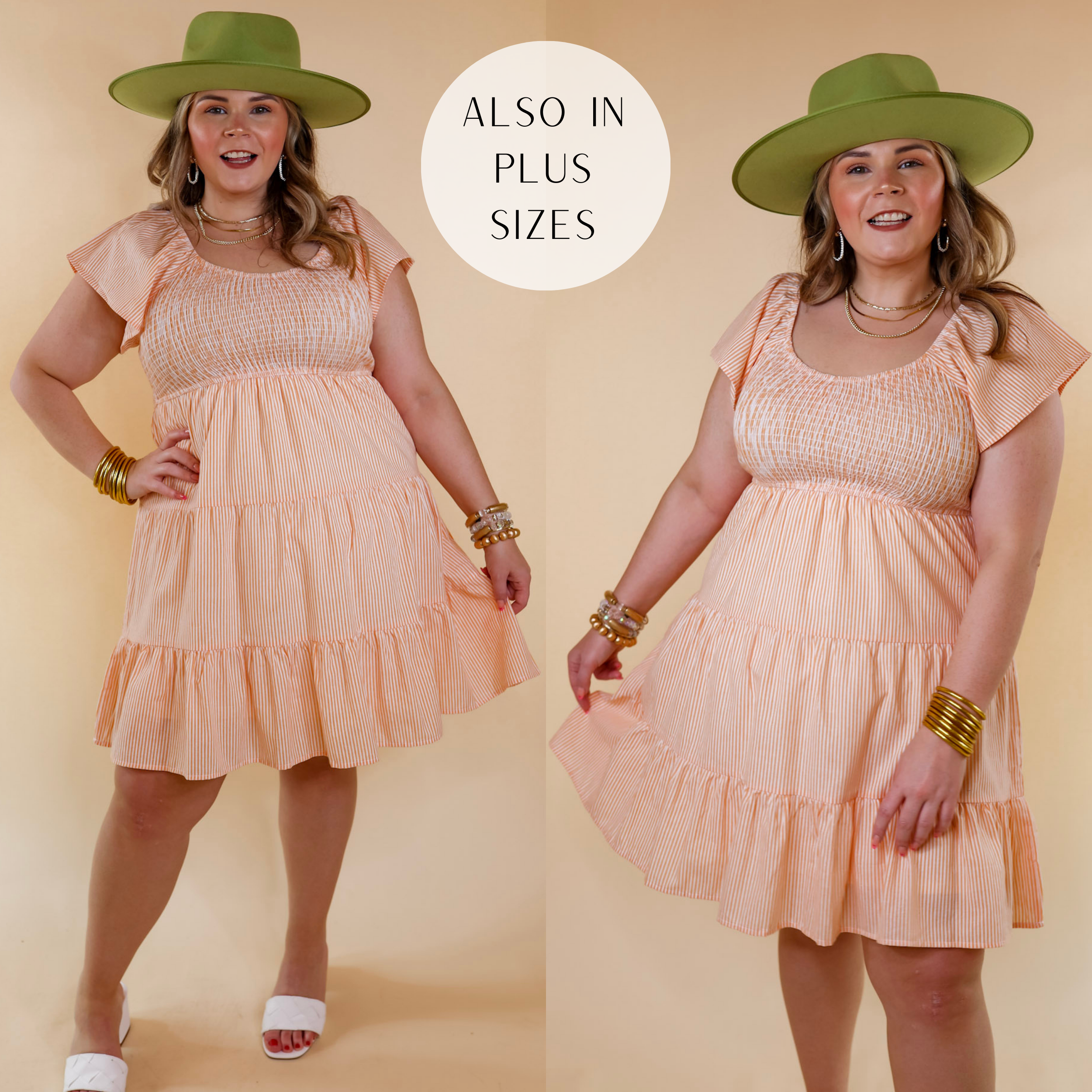 Model is wearing an orange pin stripe dress with a smocked bodice, short sleeves, and a tiered skirt. Model has this dress paired with a green hat, gold jewelry, and white sandals.