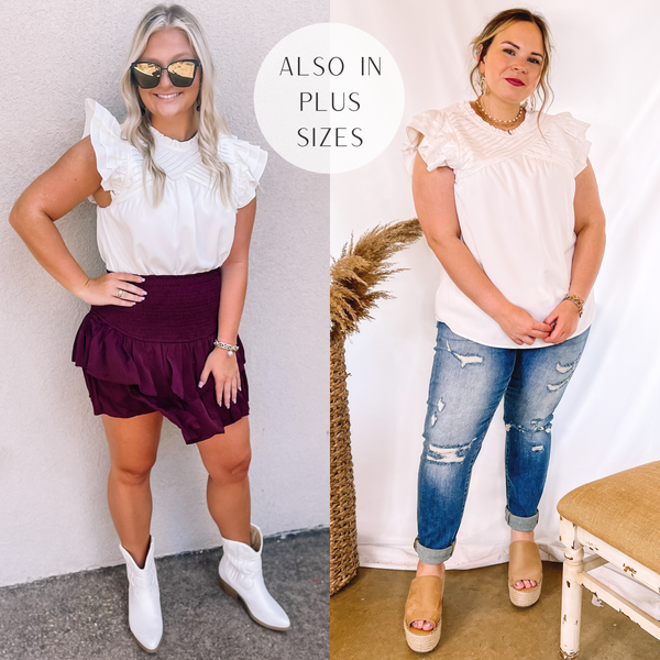 Models are wearing a white blouse with ruffle cap sleeves and pleated detailing on the chest and shoulders. Size small model has it paired with a red ruffle skirt and white booties. Size large model has it paired with cuffed boyfriend jeans, tan wedges, and gold jewelry.