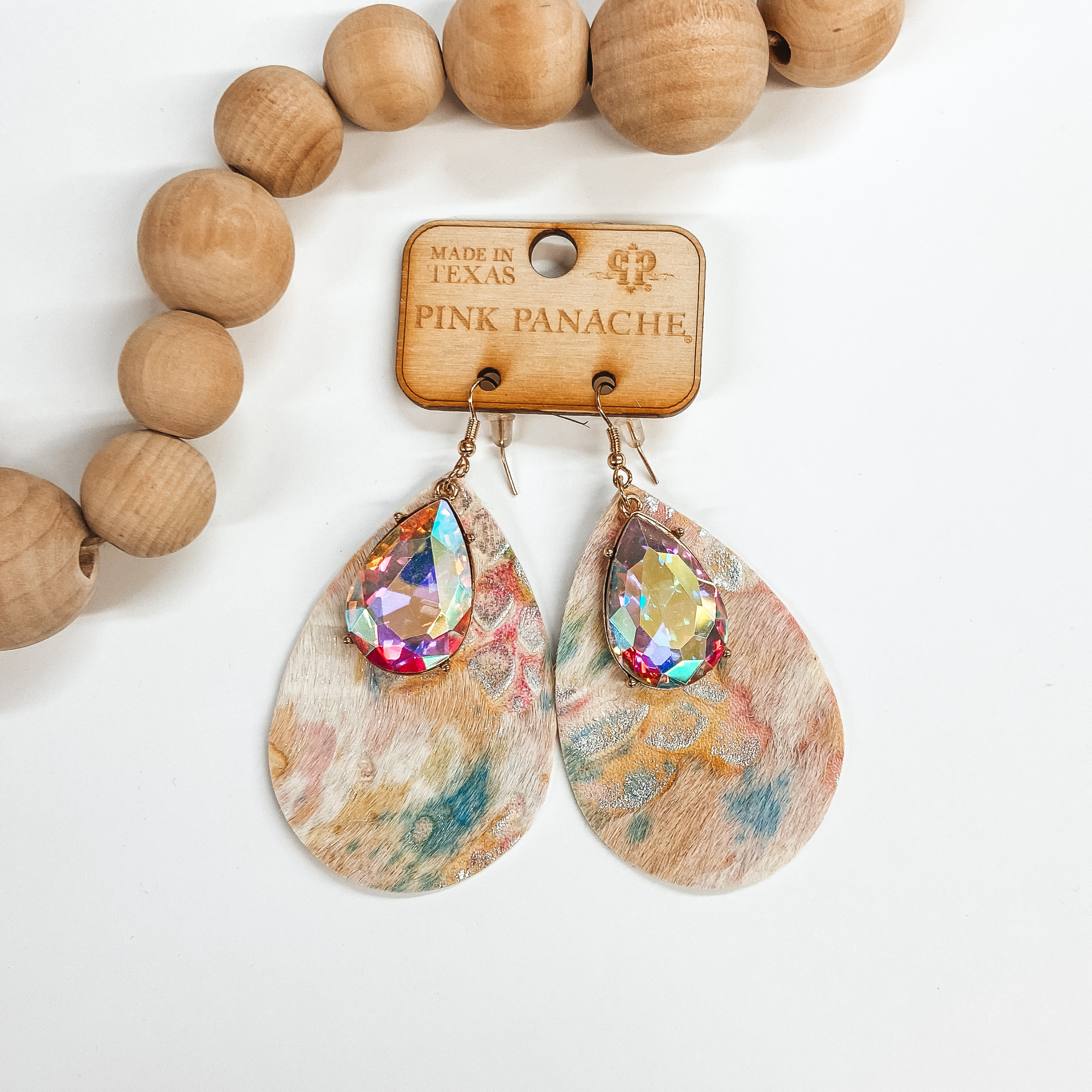 Multi color teardrop earrings with a mix animal print pattern with a teardrop AB crystal. Pictured on white background with wooden beads.