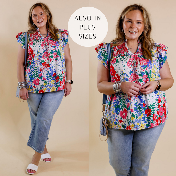 Model is wearing a a white floral top with ruffle cap sleeves and smocked detailing on the upper. Model has it paired with cropped jeans, white heels, and silver jewelry.