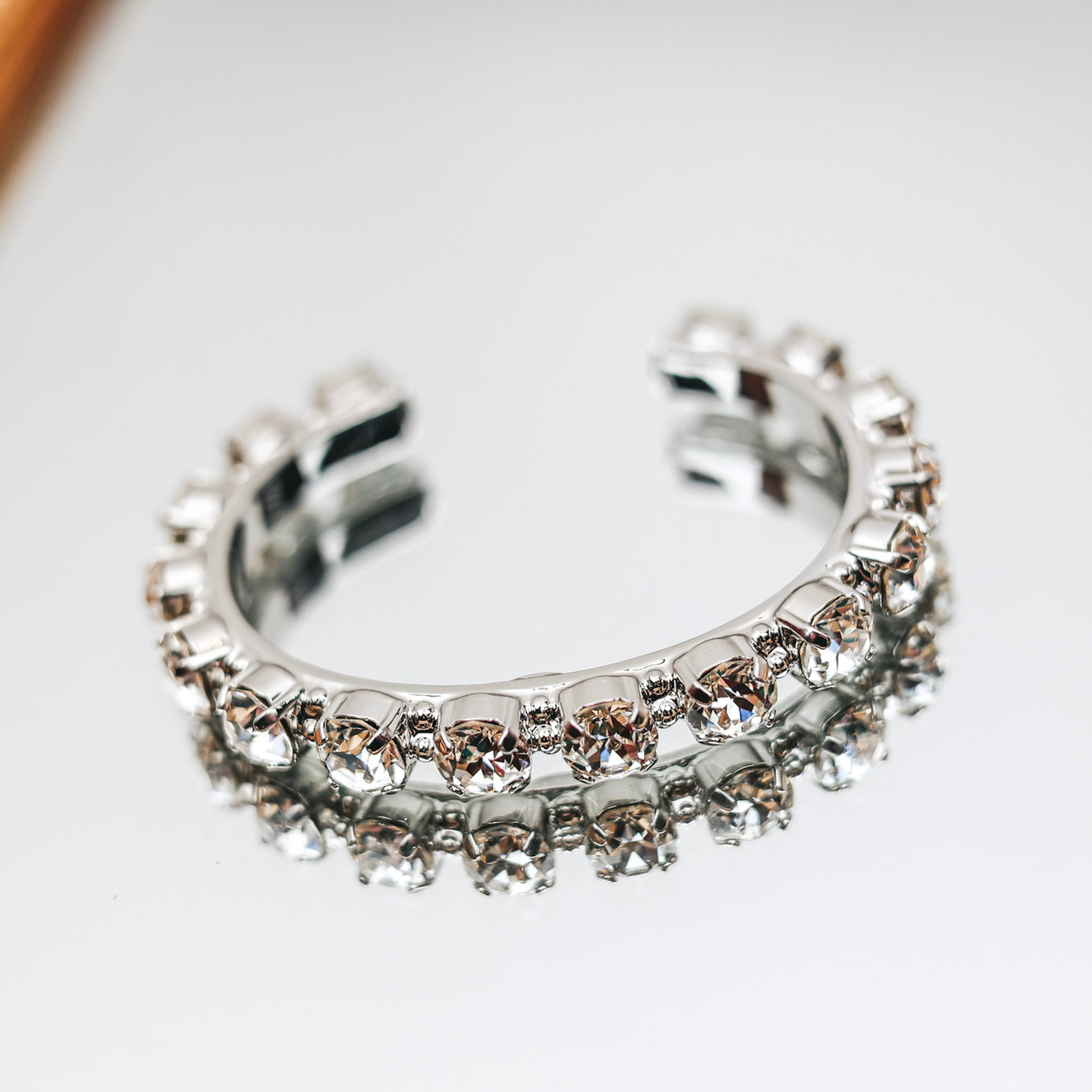 A silver tone cuff bracelet with clear crystals along the cuff.