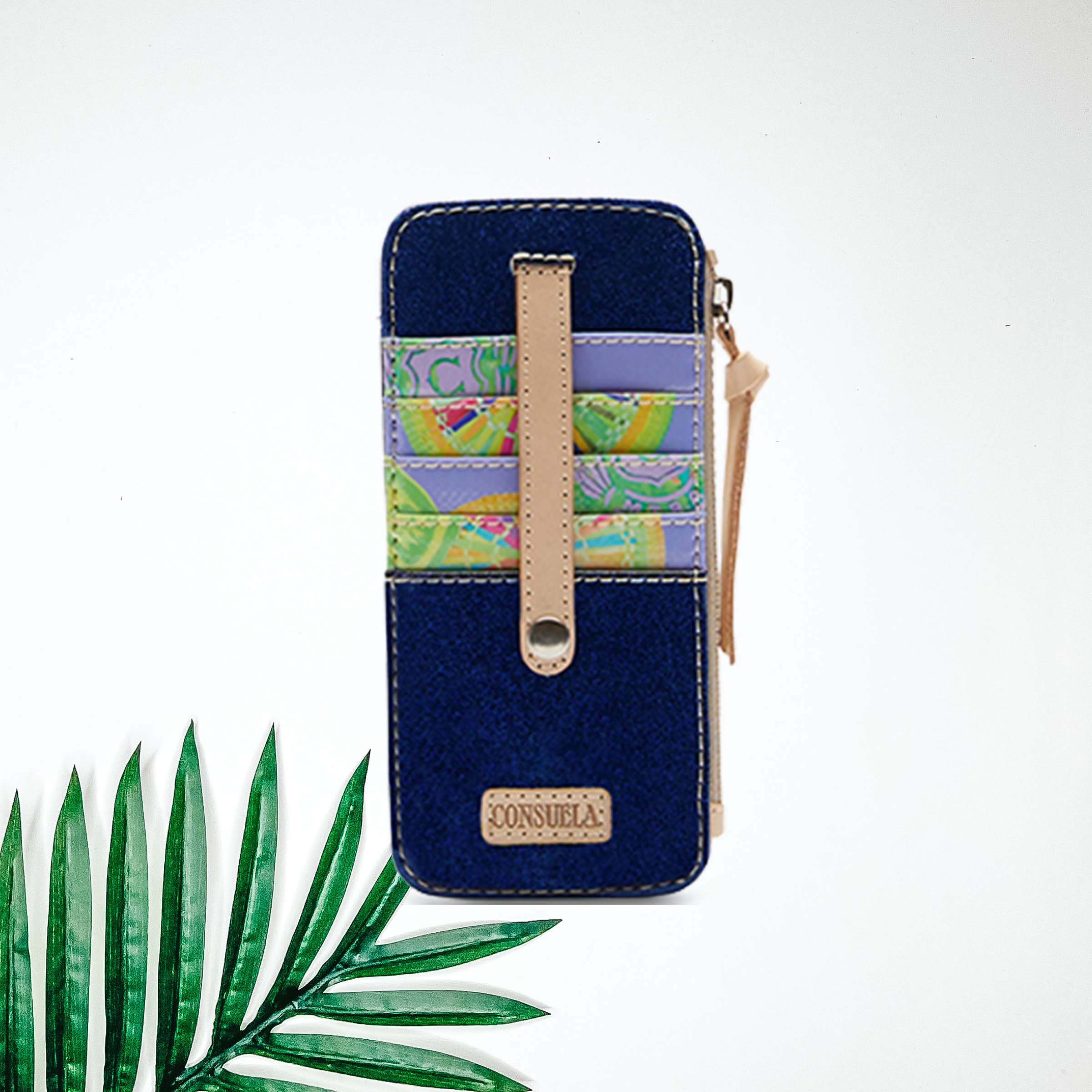 A blue glitter card organizer wallet with leather detailing. Pictured on white background with a palm leaf.