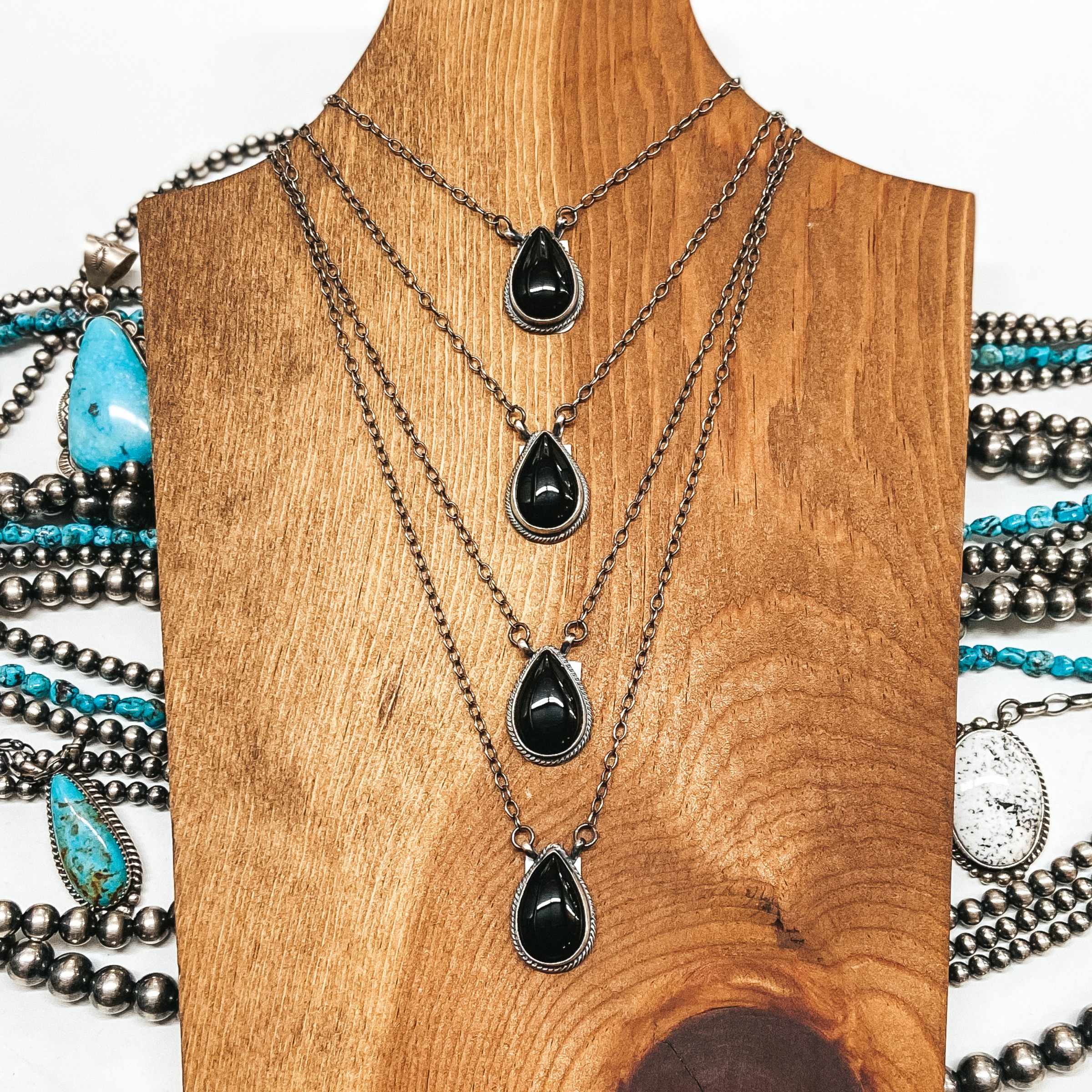4 Sterling silver chain necklaces with black onyx teardrop pendants pictured on wooden background with sterling silver and turquoise jewelry
