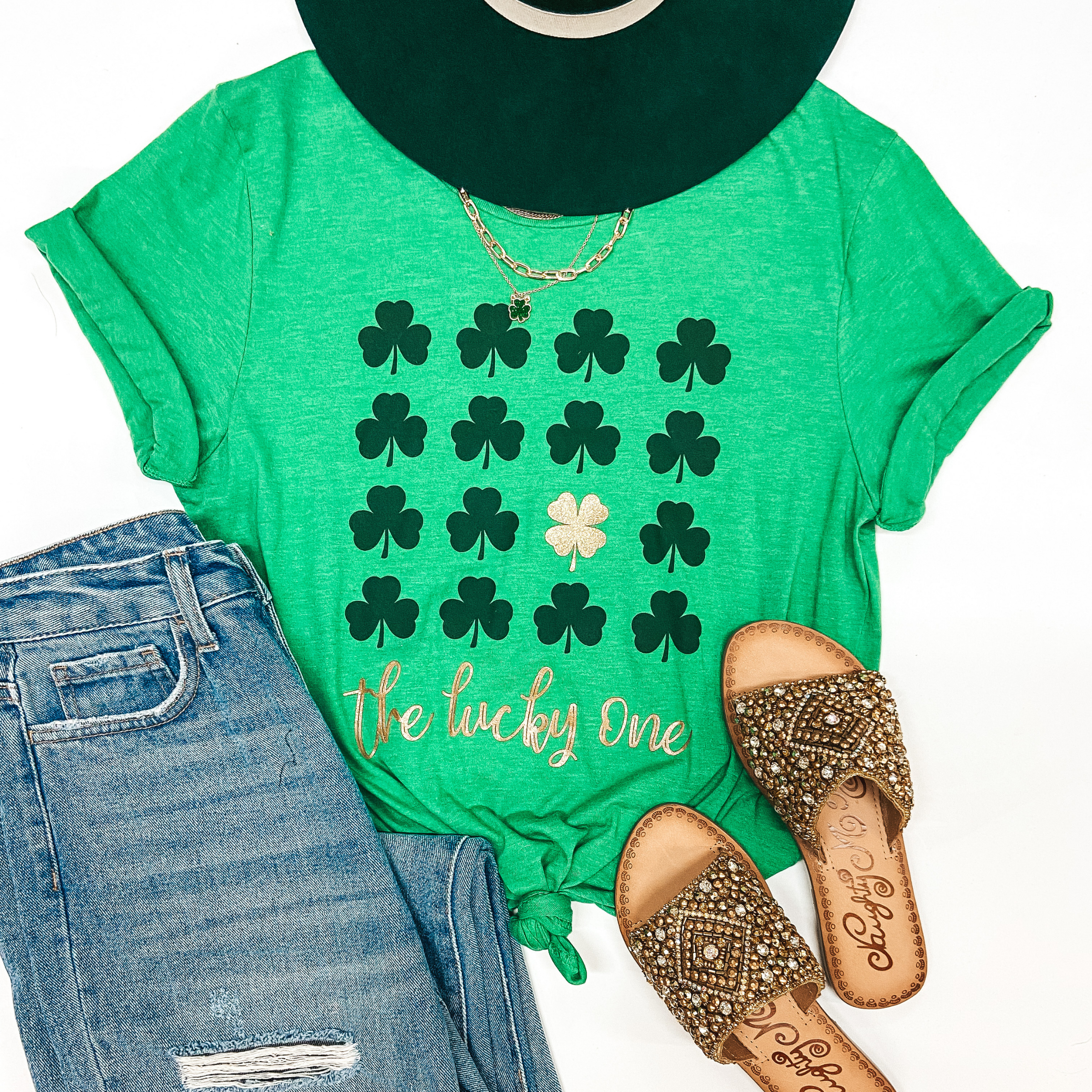 A green graphic tee that has dark green clovers and gold writing that says "The Lucky Ones"