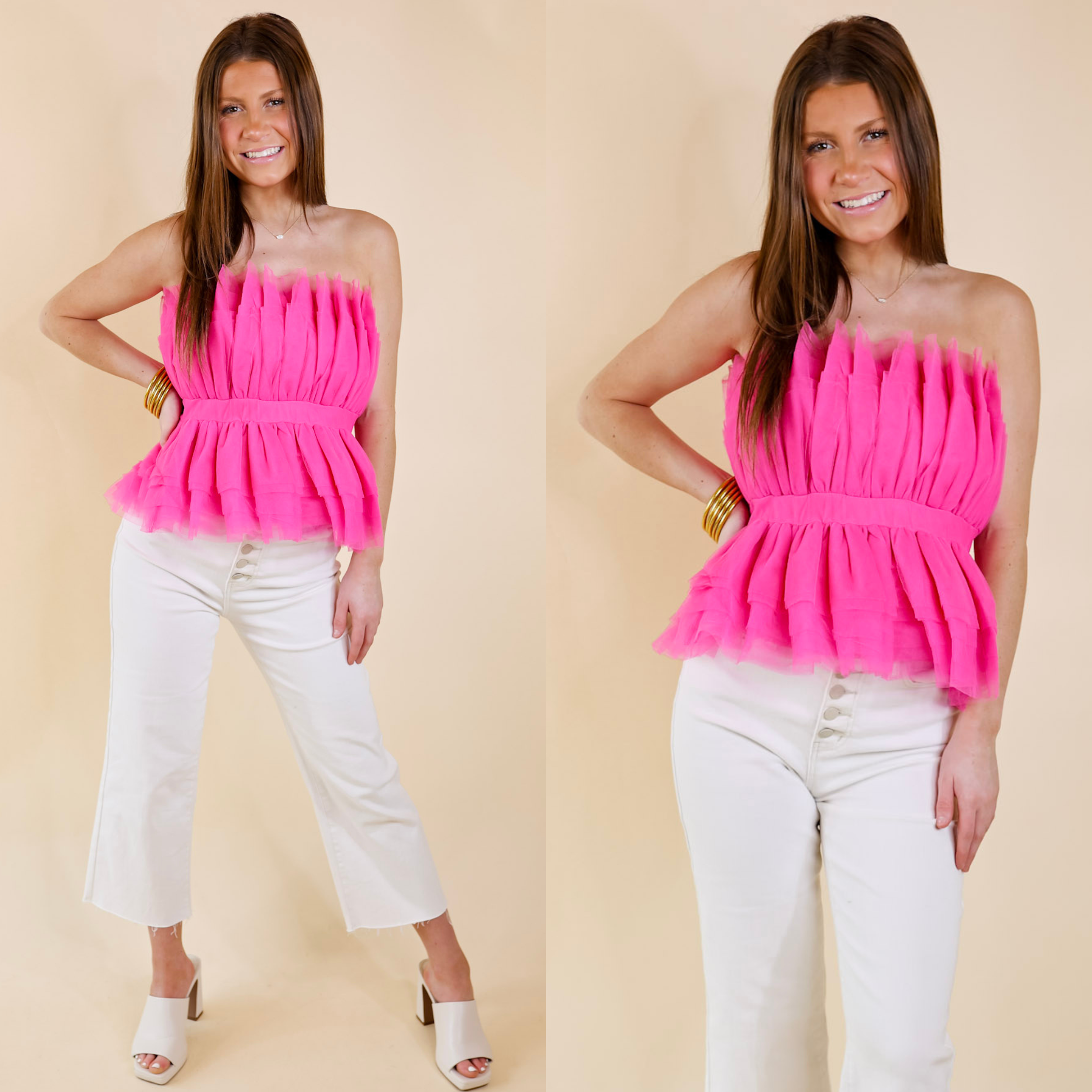 Model is wearing a strapless top made of tulle ruffles that is hot pink. Model has this top paired with white jeans, ivory heels, and gold jewelry.