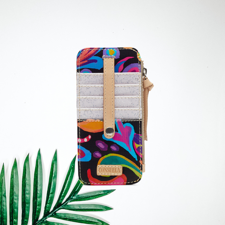 A black card organizing wallet with a colorful paisley print. Pictured on white background with a palm leaf.